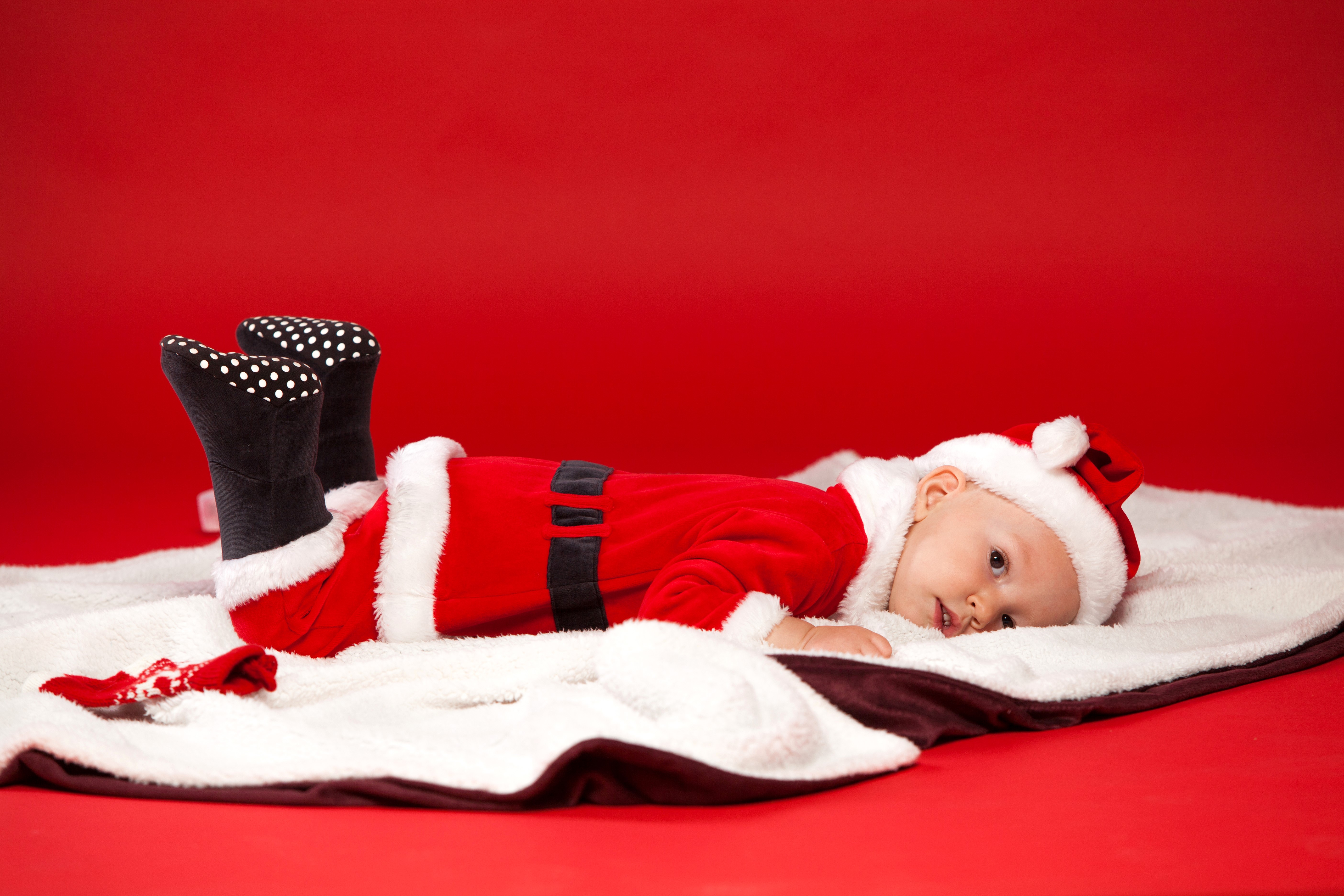 Baby in Santa Claus costume on red background HD Wallpaper