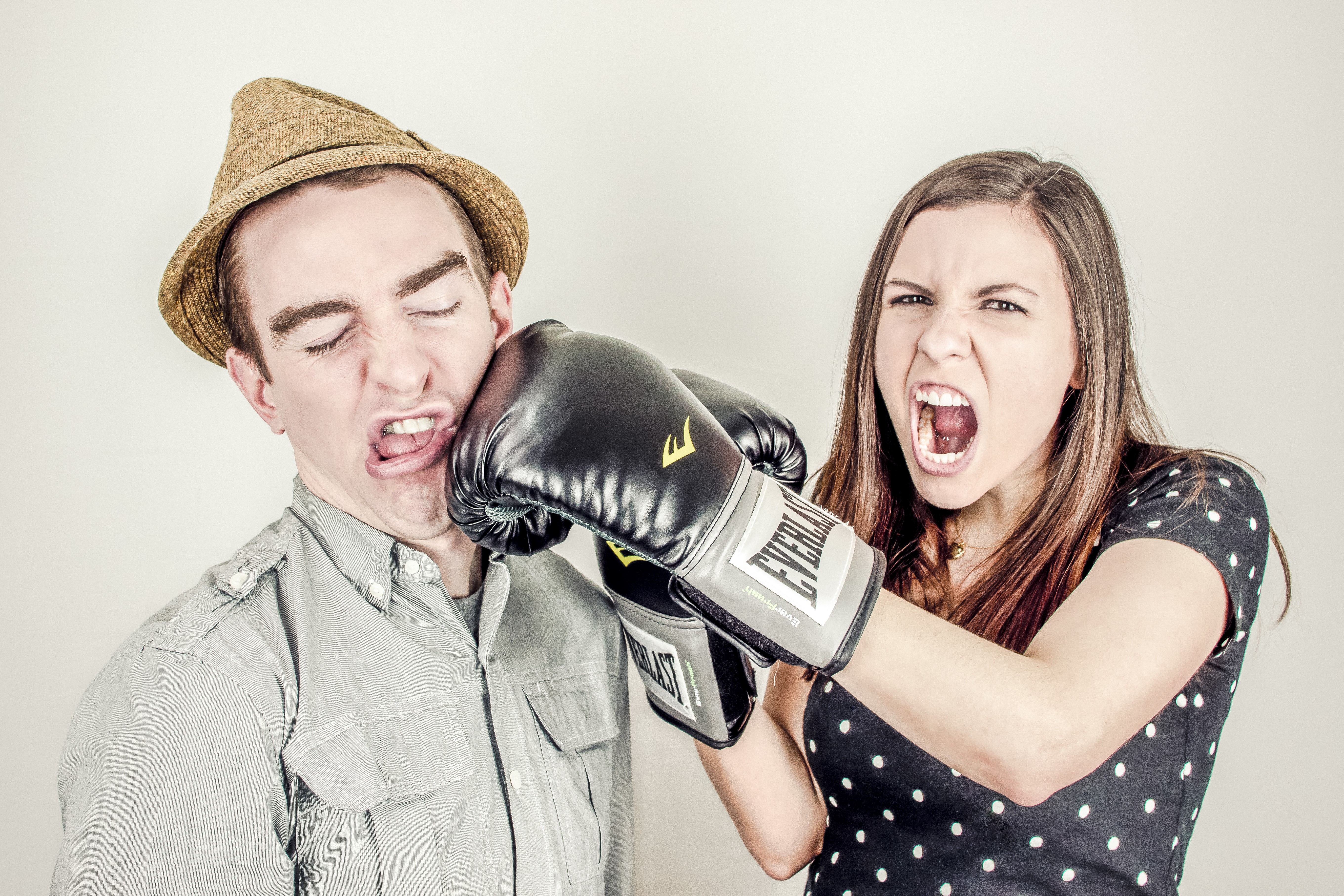 Man in hat getting punched by woman in boxing gloves HD Wallpaper