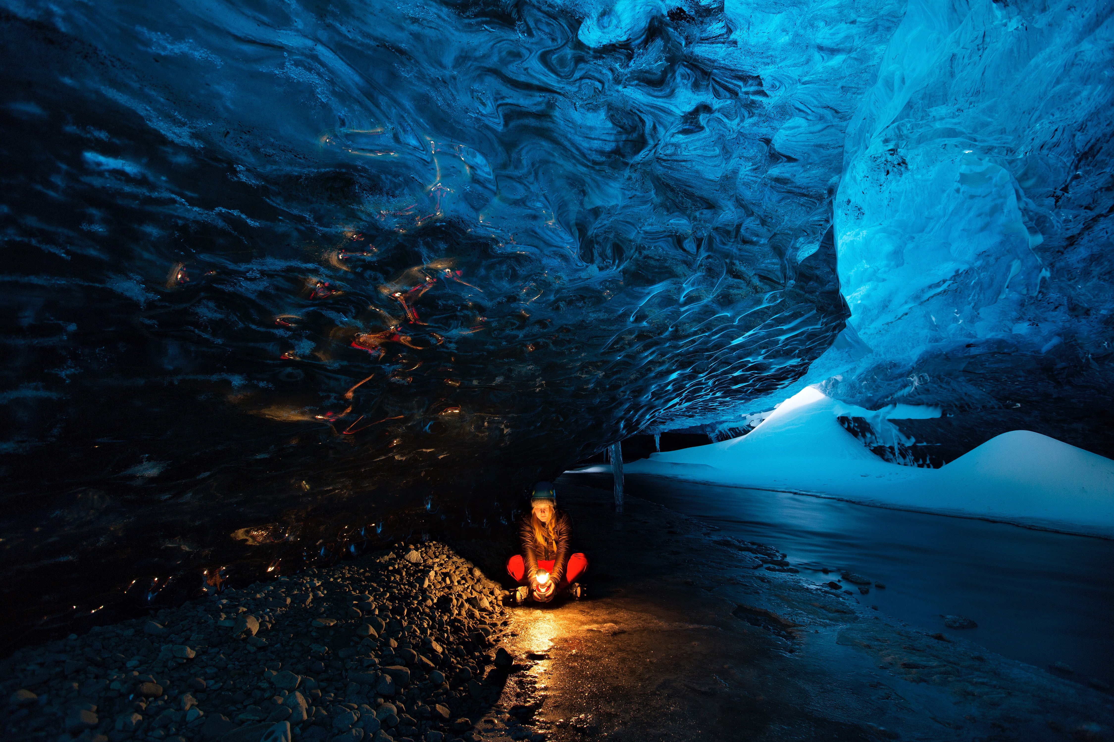 Person with lamp in blue ice cave HD Wallpaper