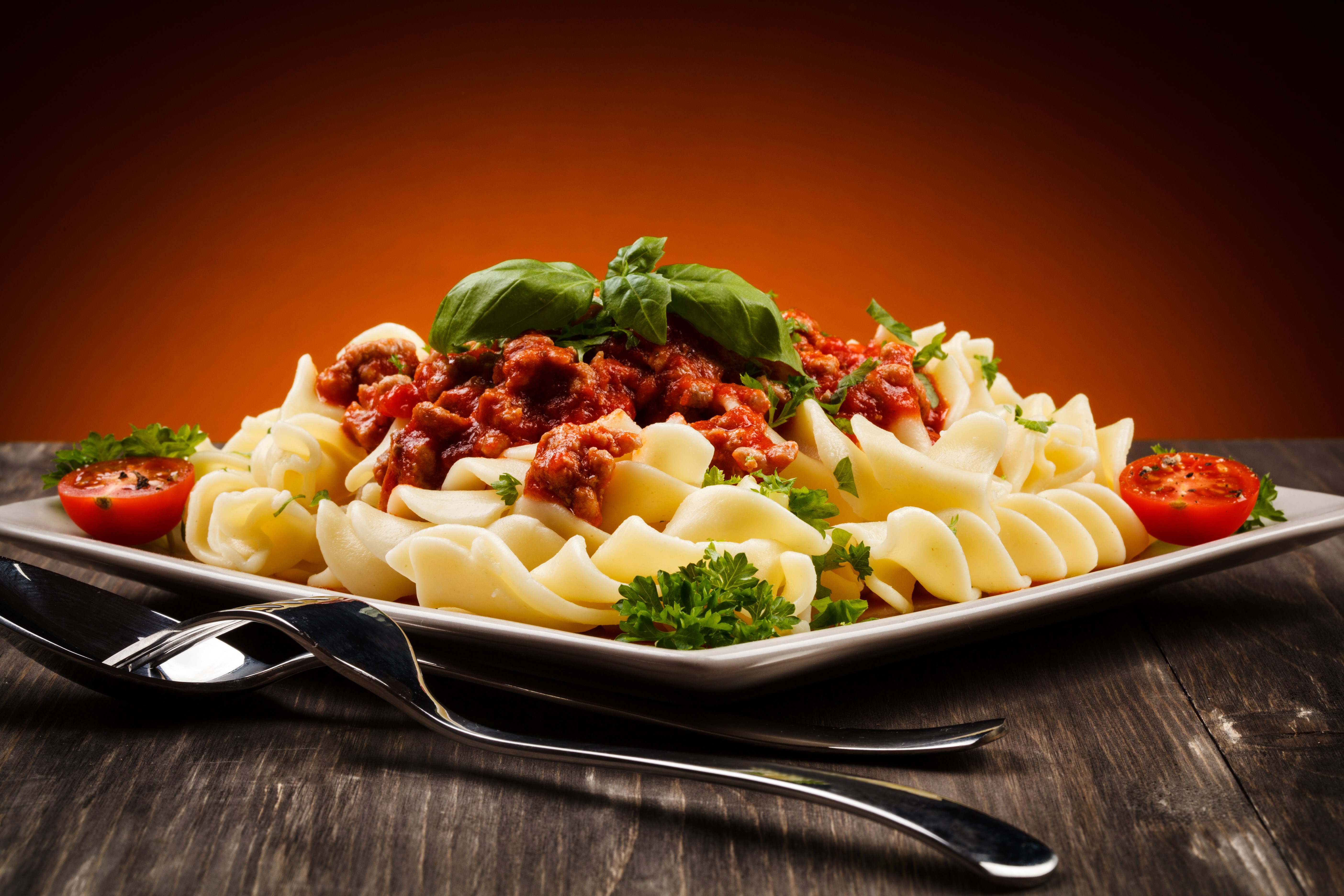Pasta with meat sauce, tomatoes, and basil on a plate HD Wallpaper