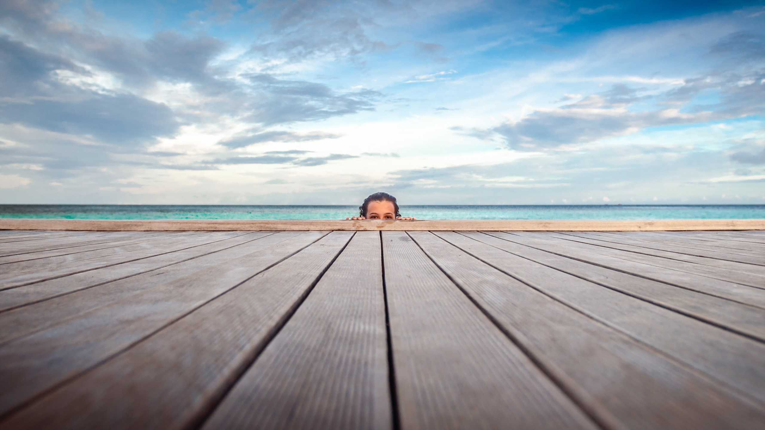 Person peeking over wooden planks at the sea HD Wallpaper