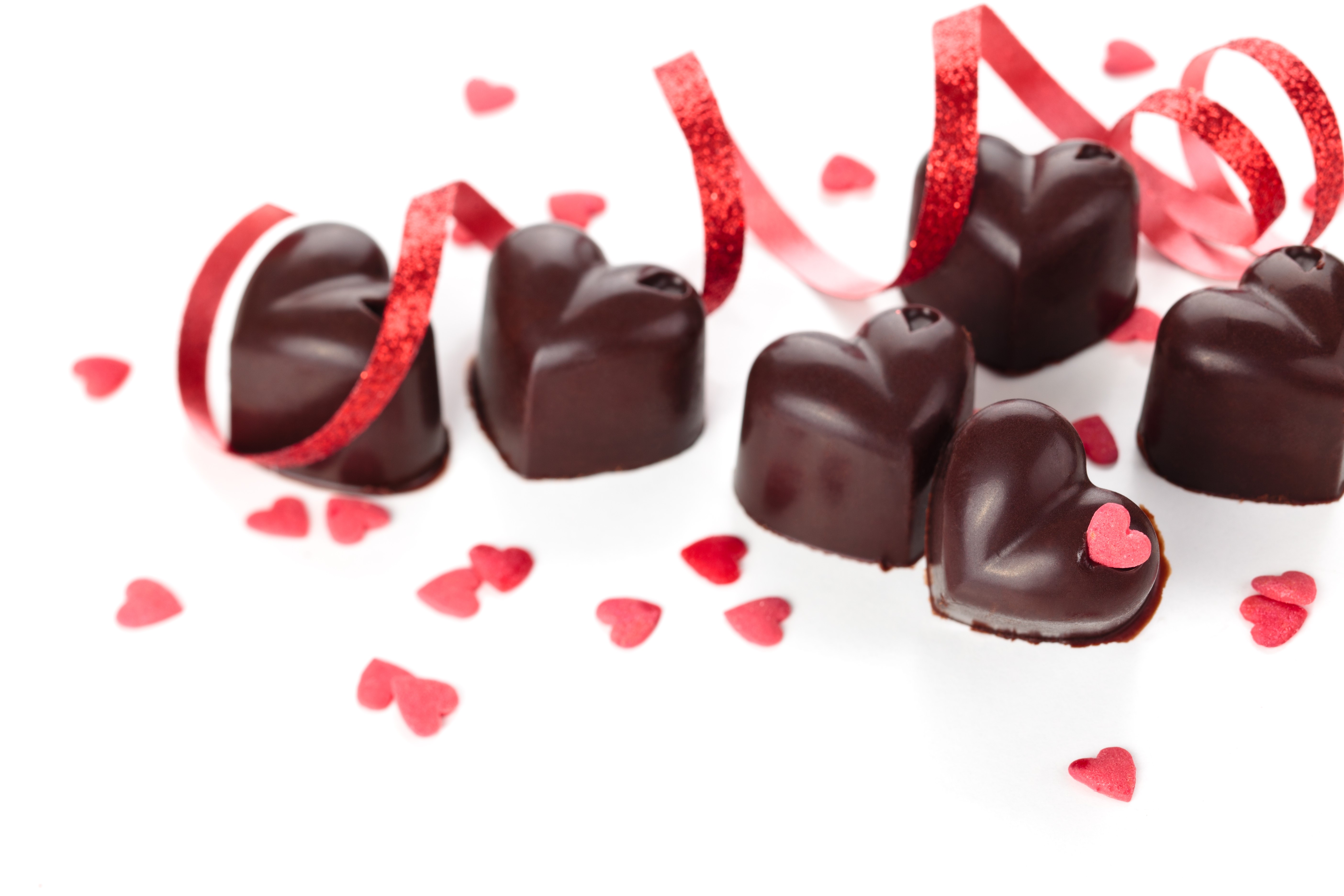 Heart-shaped chocolates with red ribbon and confetti HD Wallpaper