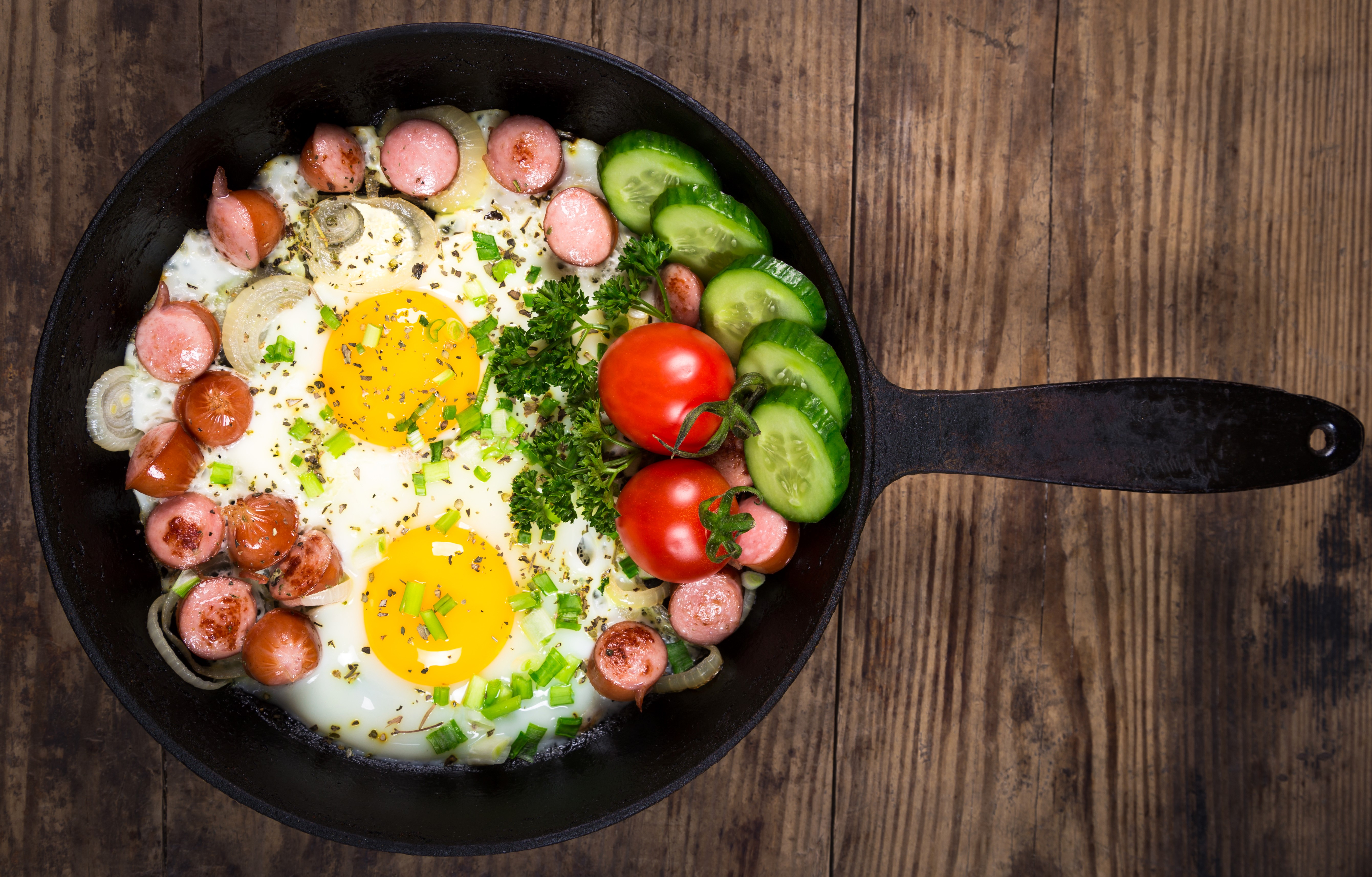 Fried eggs with sausages, tomatoes, and cucumbers in a frying pan HD Wallpaper