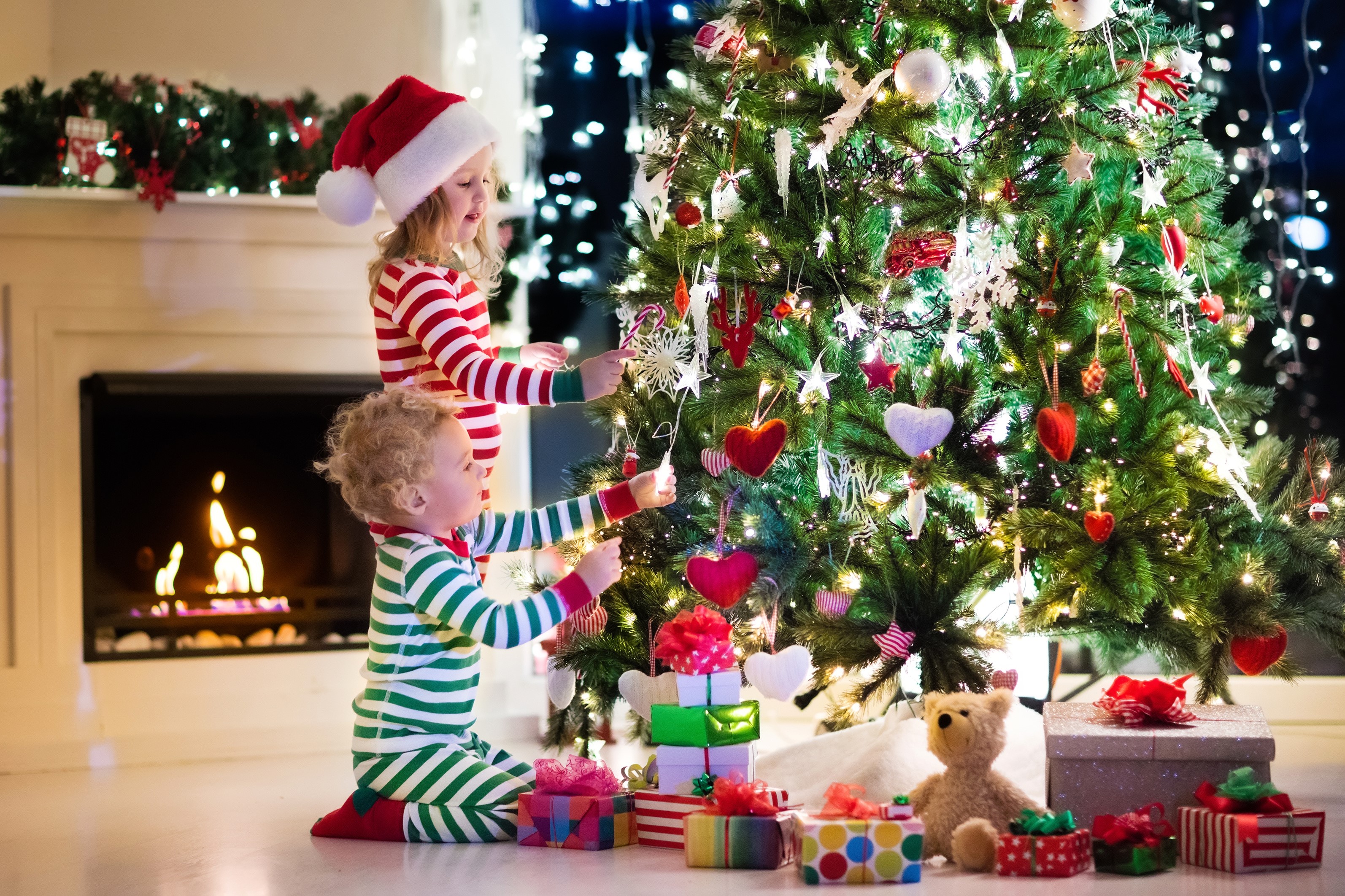Children decorating a Christmas tree by a fireplace HD Wallpaper