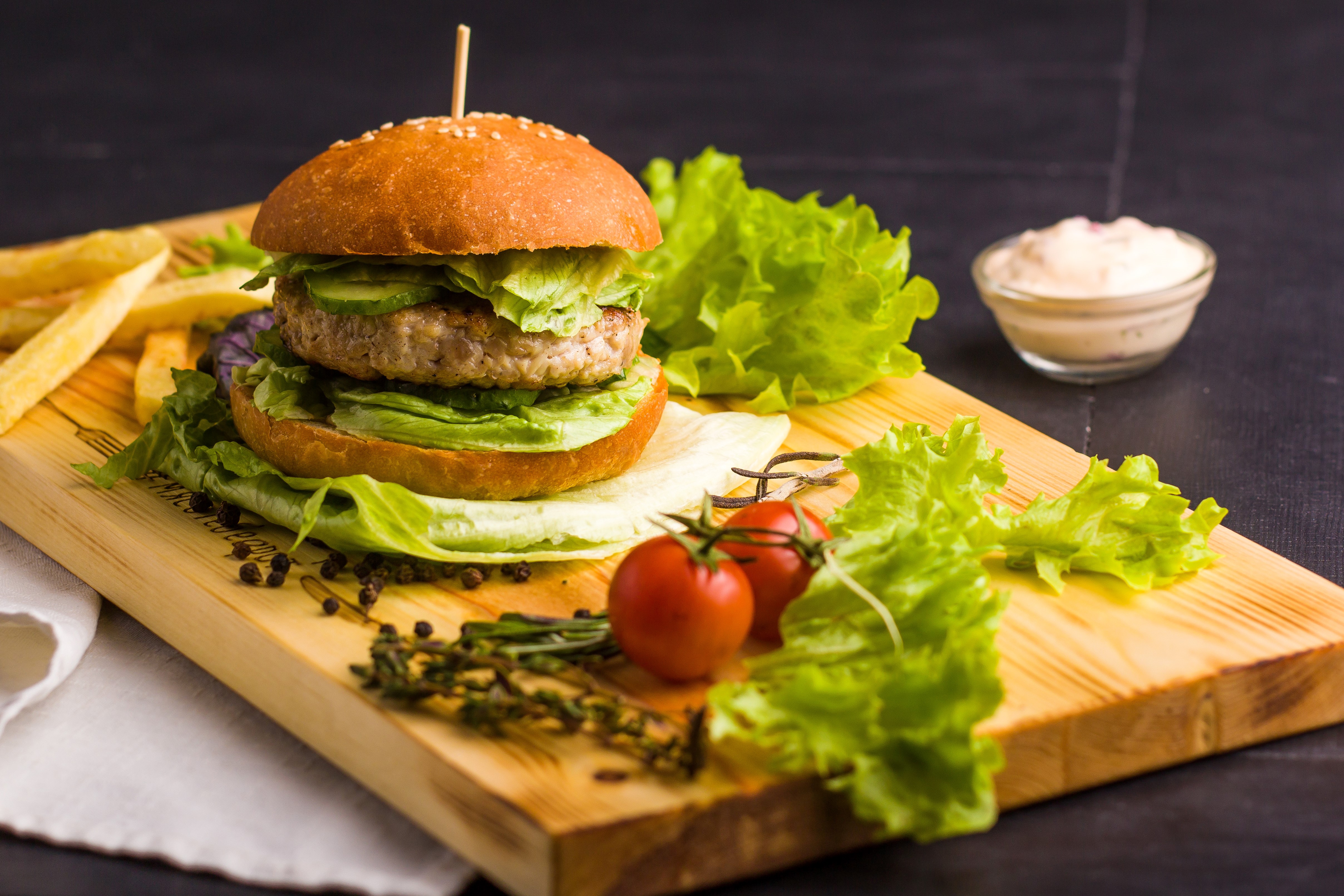 Hamburger with fries and sauce on a cutting board HD Wallpaper