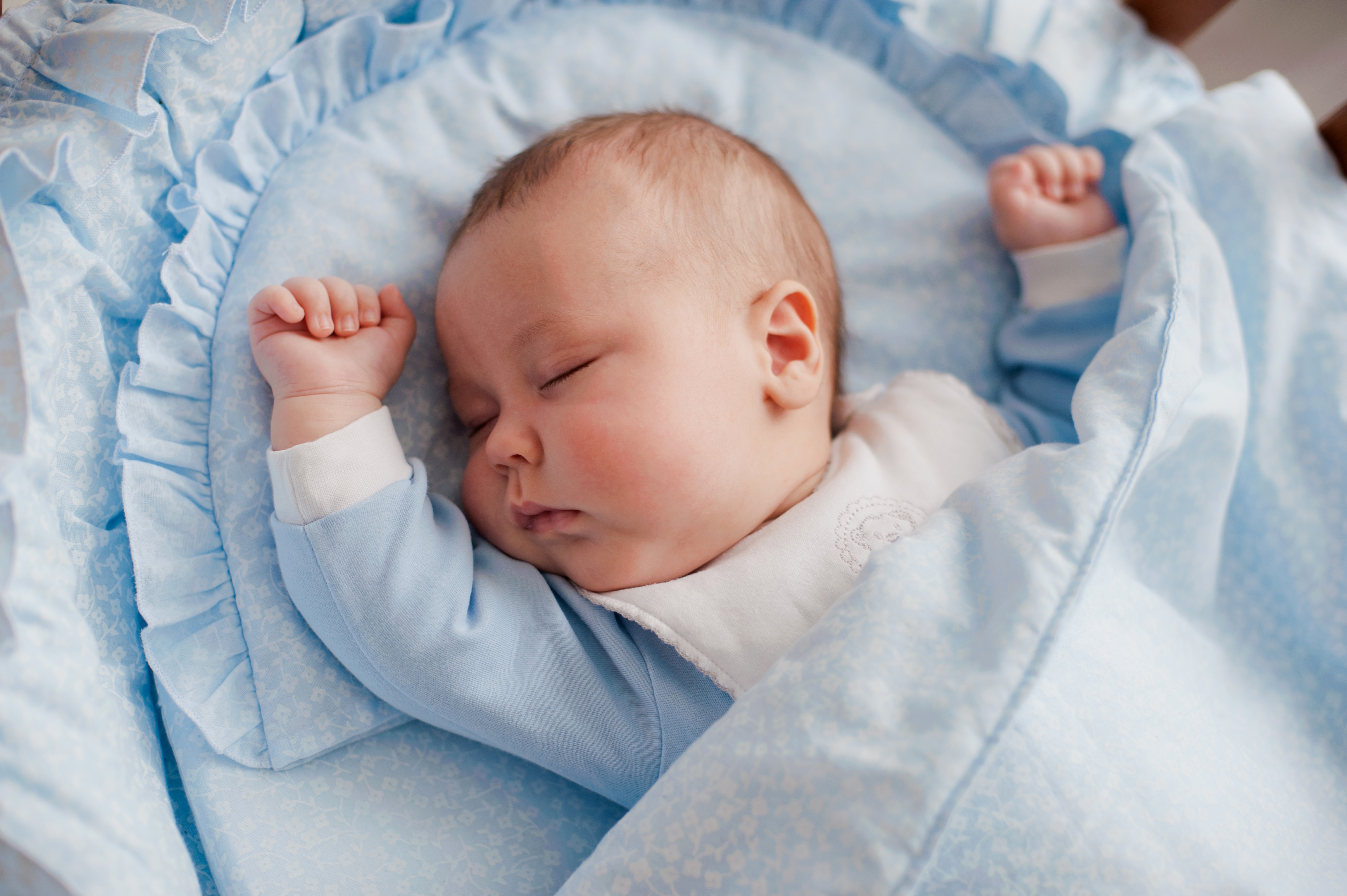 Infant sleeping in a blue bassinet HD Wallpaper