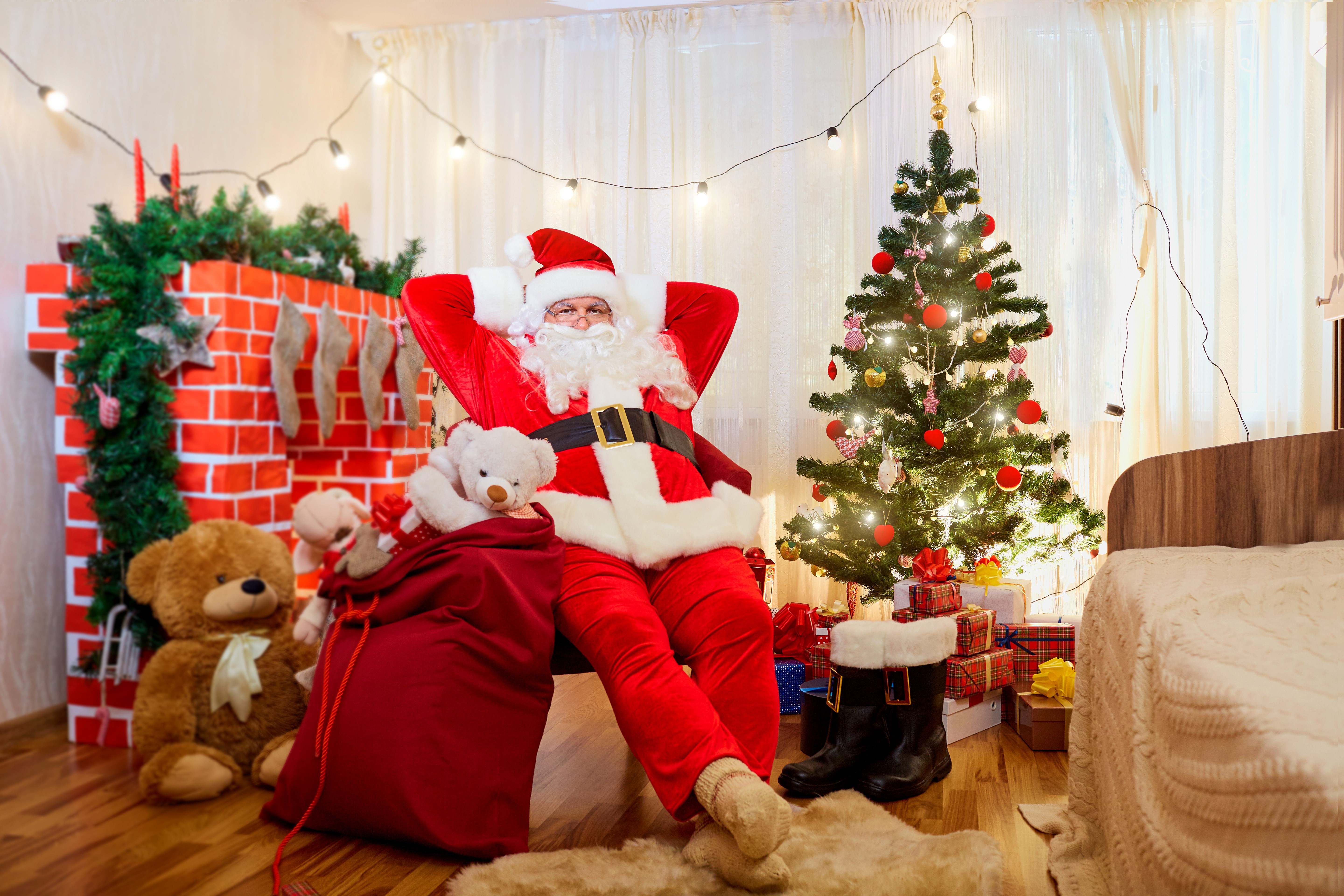 Santa Claus relaxing by a Christmas tree with gifts HD Wallpaper