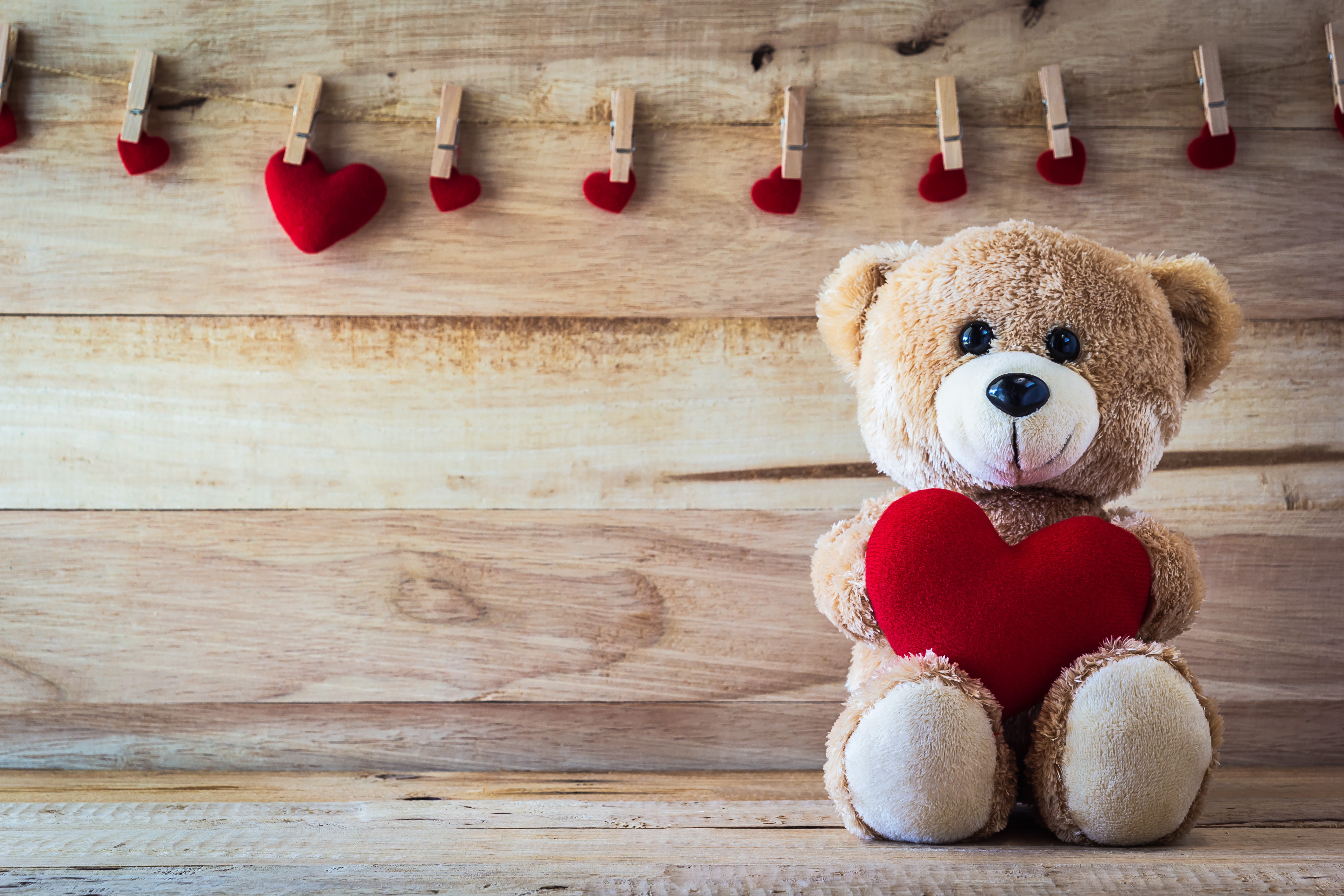 Teddy bear holding a red heart with hearts on a string HD Wallpaper