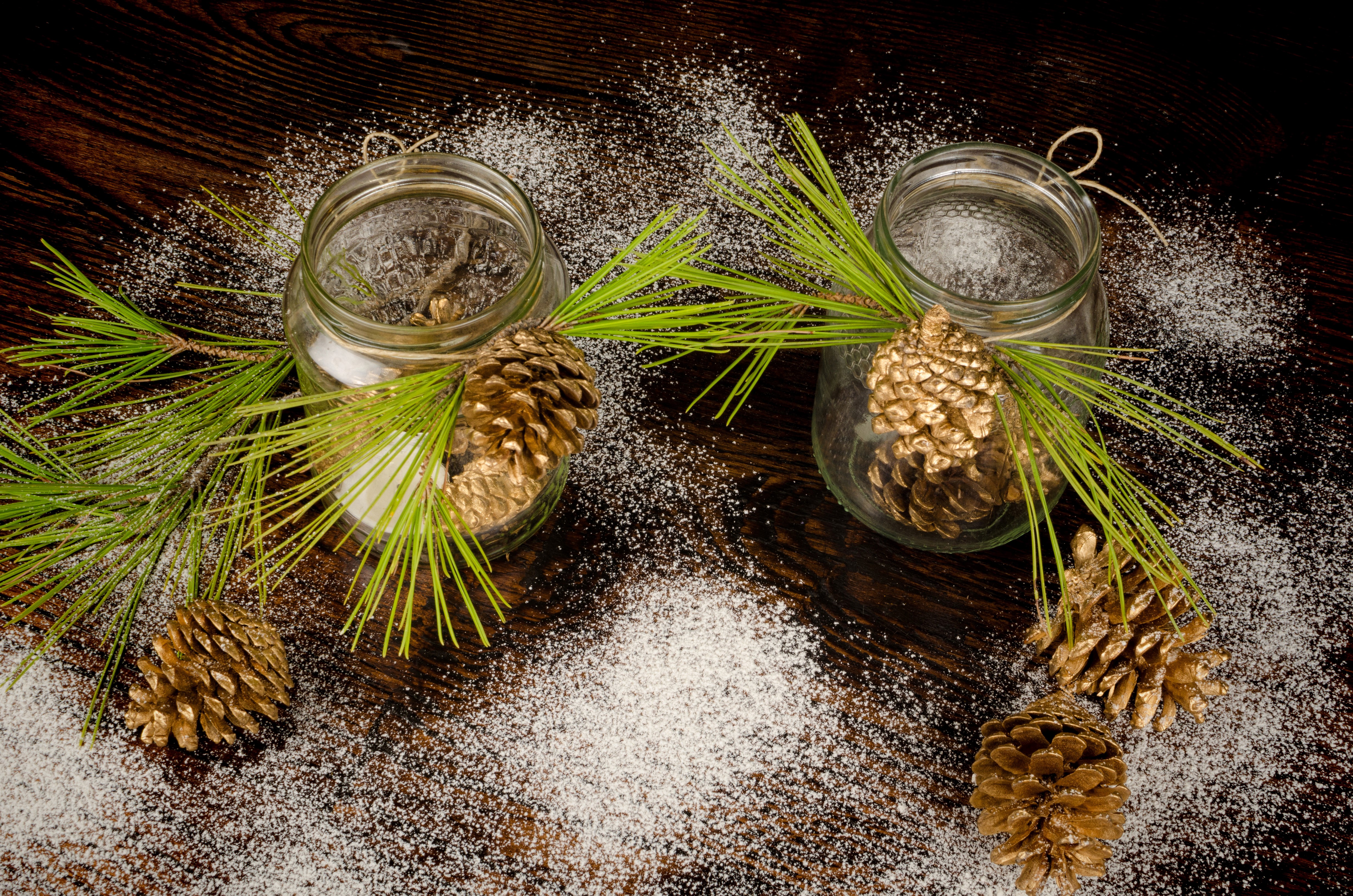 Two jars with pine cones and pine branches on wood HD Wallpaper