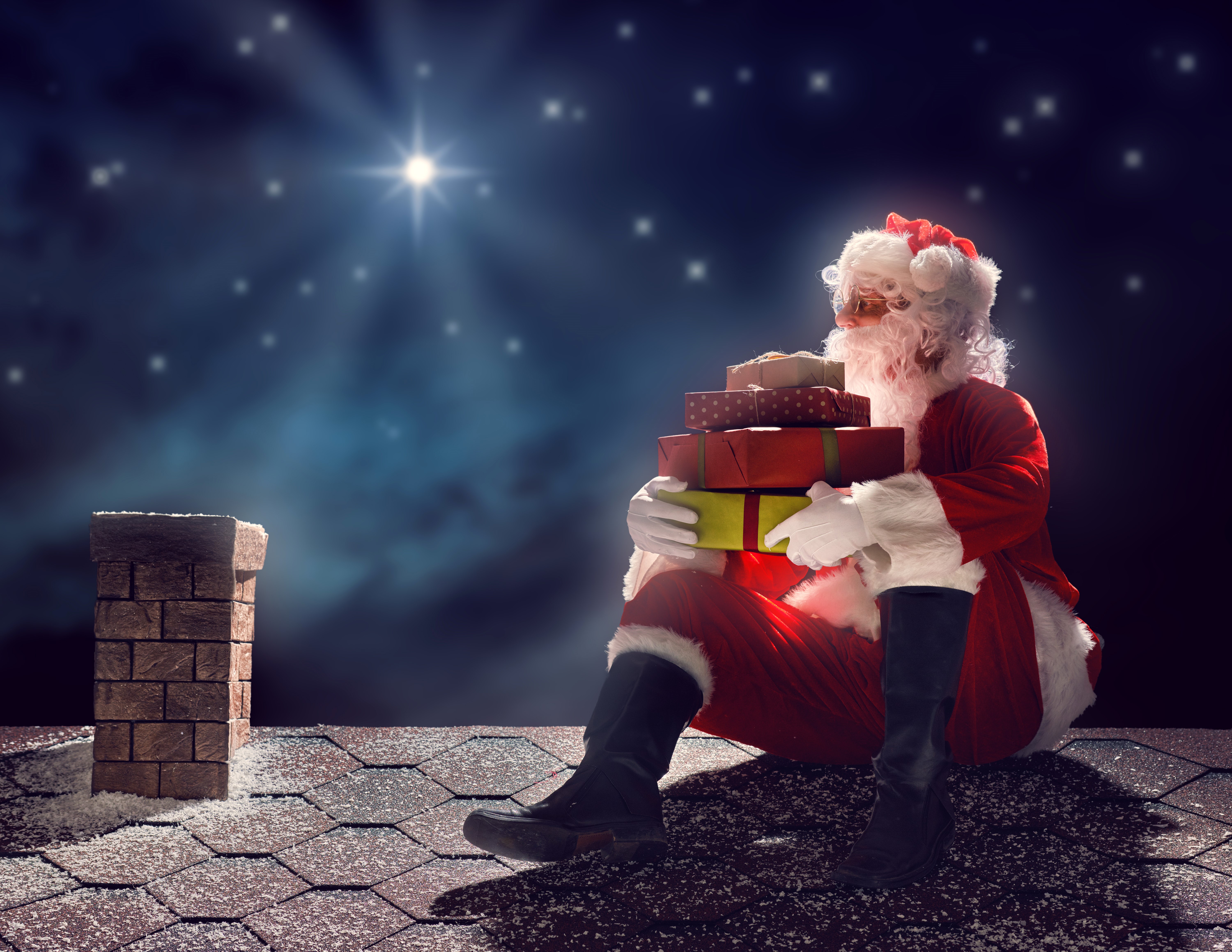 Santa Claus sitting on a roof with gifts HD Wallpaper