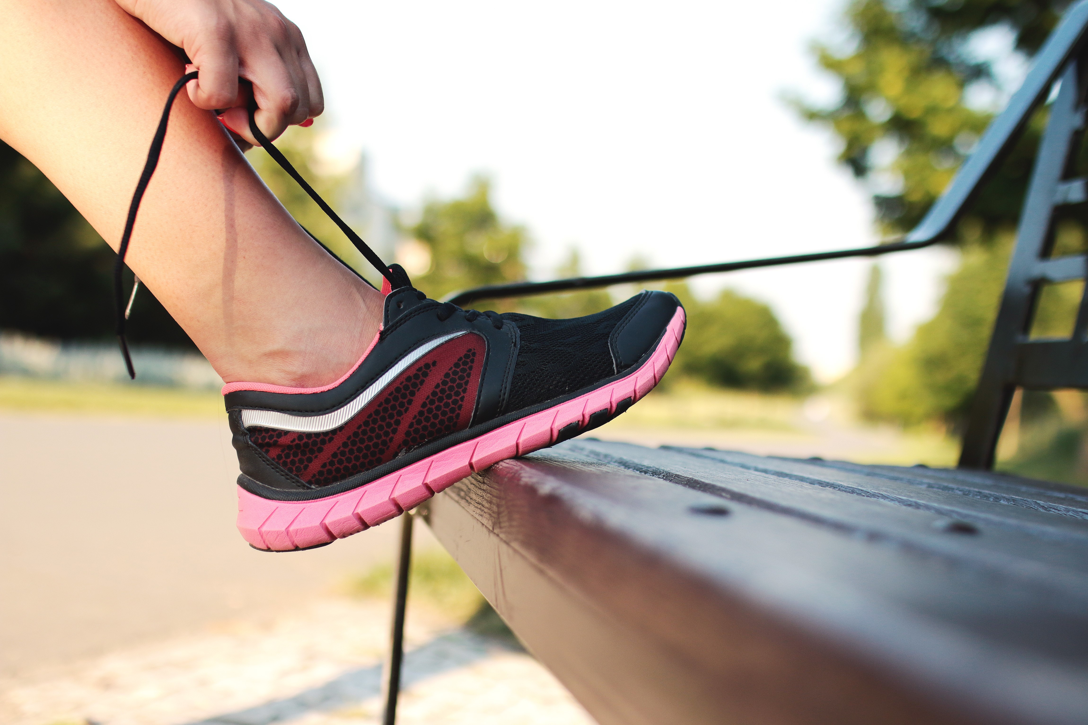 Person Tying Athletic Shoe on Bench HD Wallpaper