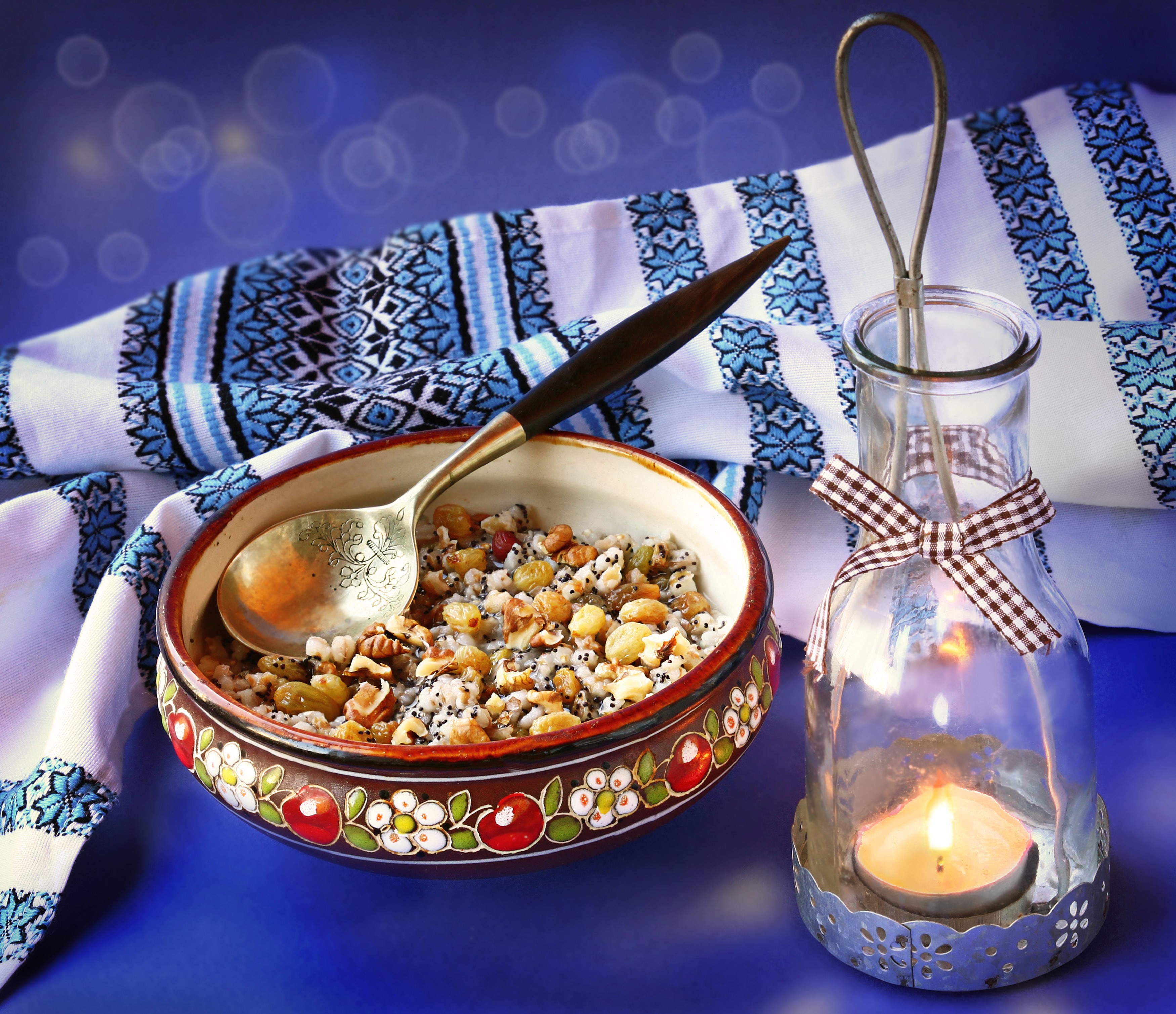 Kutia with spoon and candle lantern on embroidered cloth HD Wallpaper