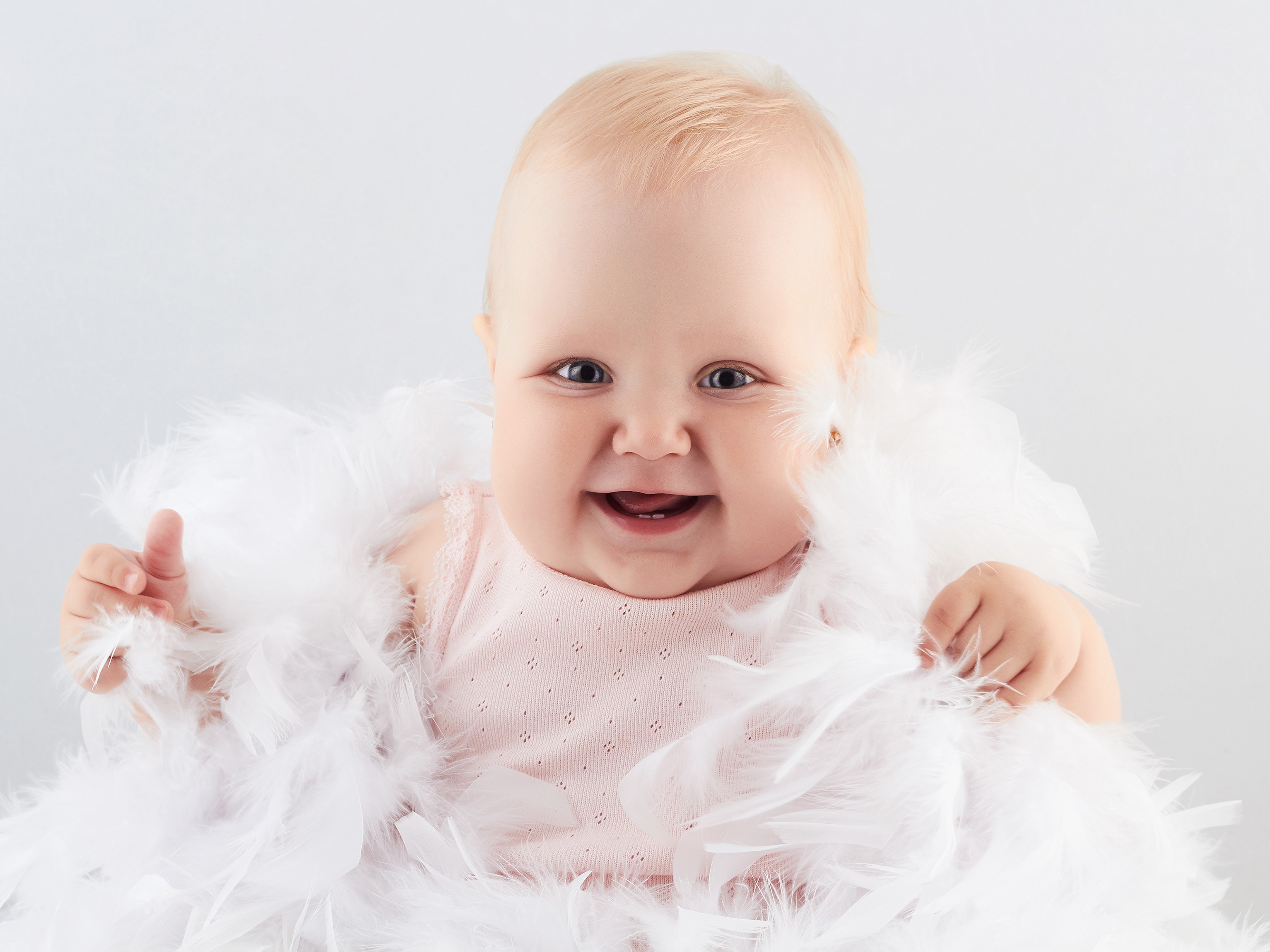 Baby smiling with white feathers HD Wallpaper