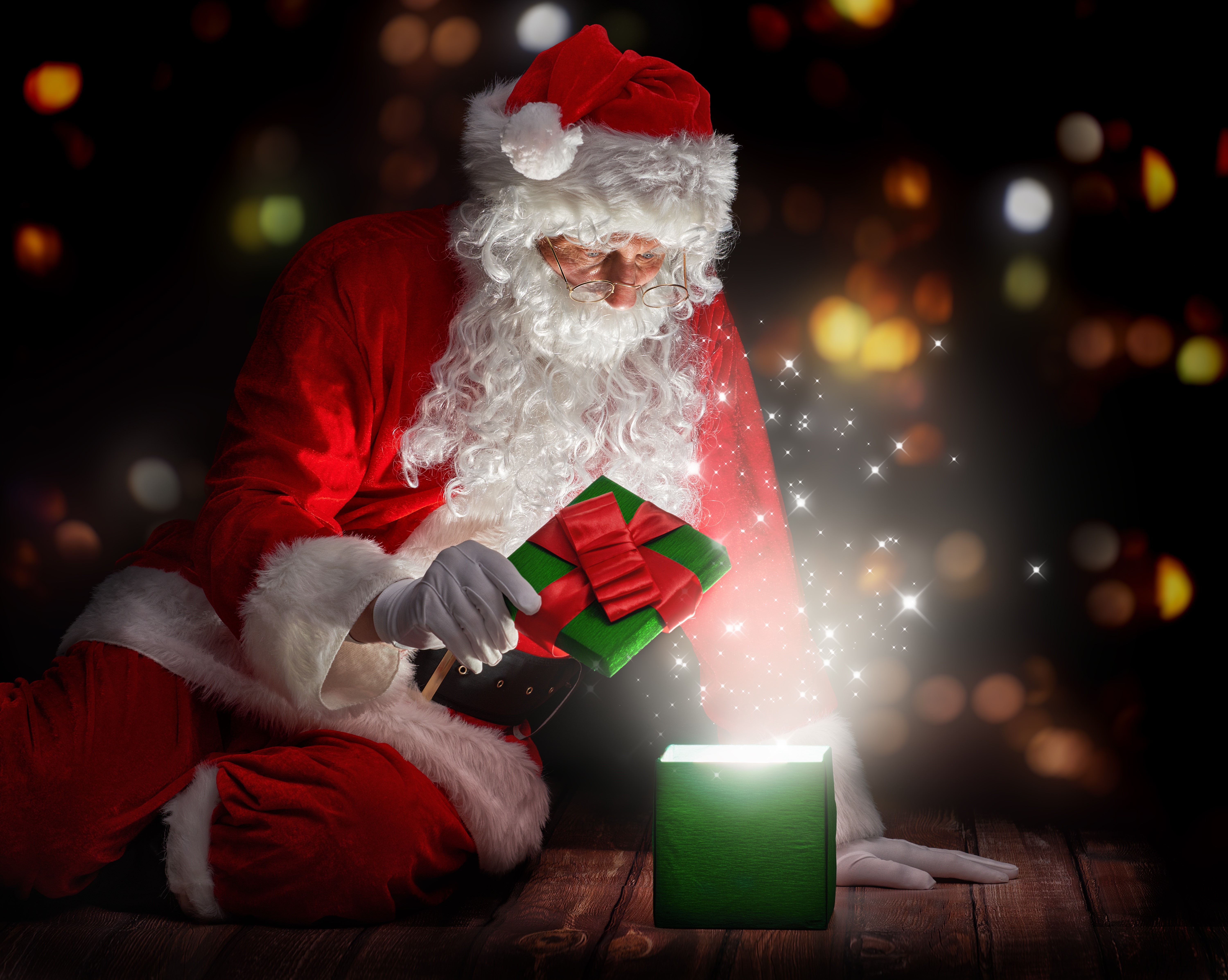 Santa Claus opening a glowing gift box HD Wallpaper