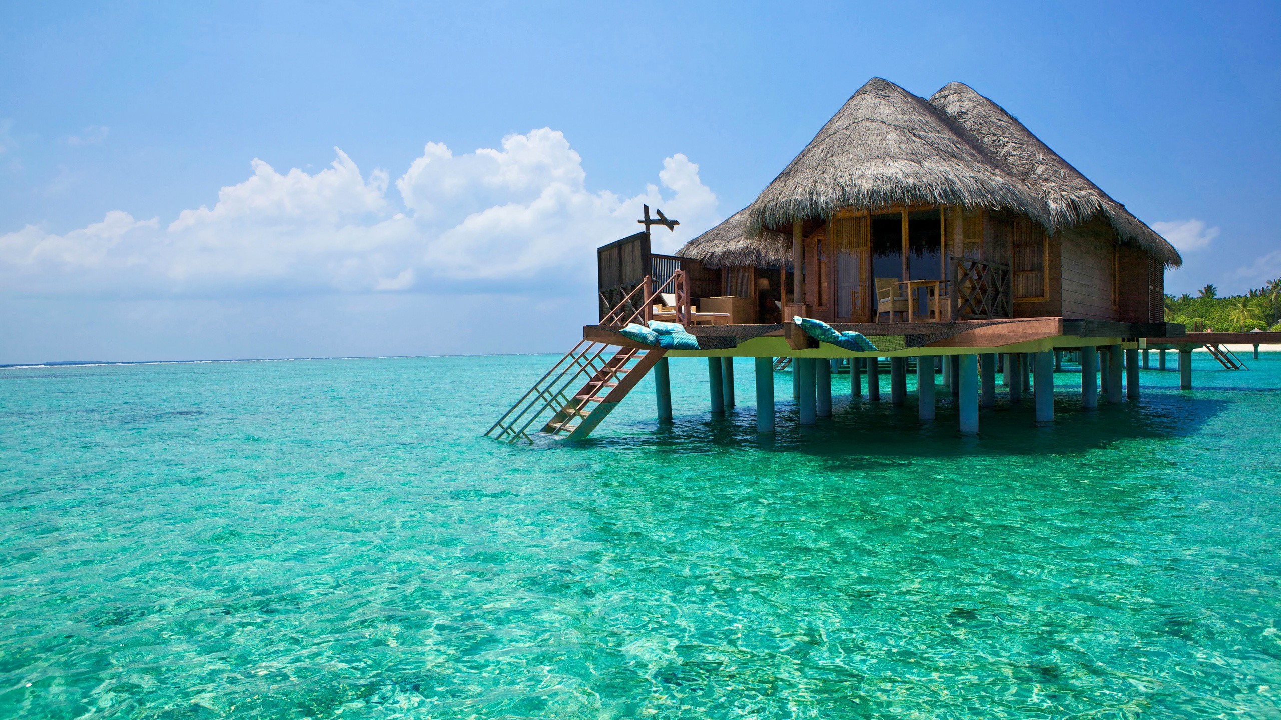 Overwater bungalow on turquoise water under blue sky HD Wallpaper