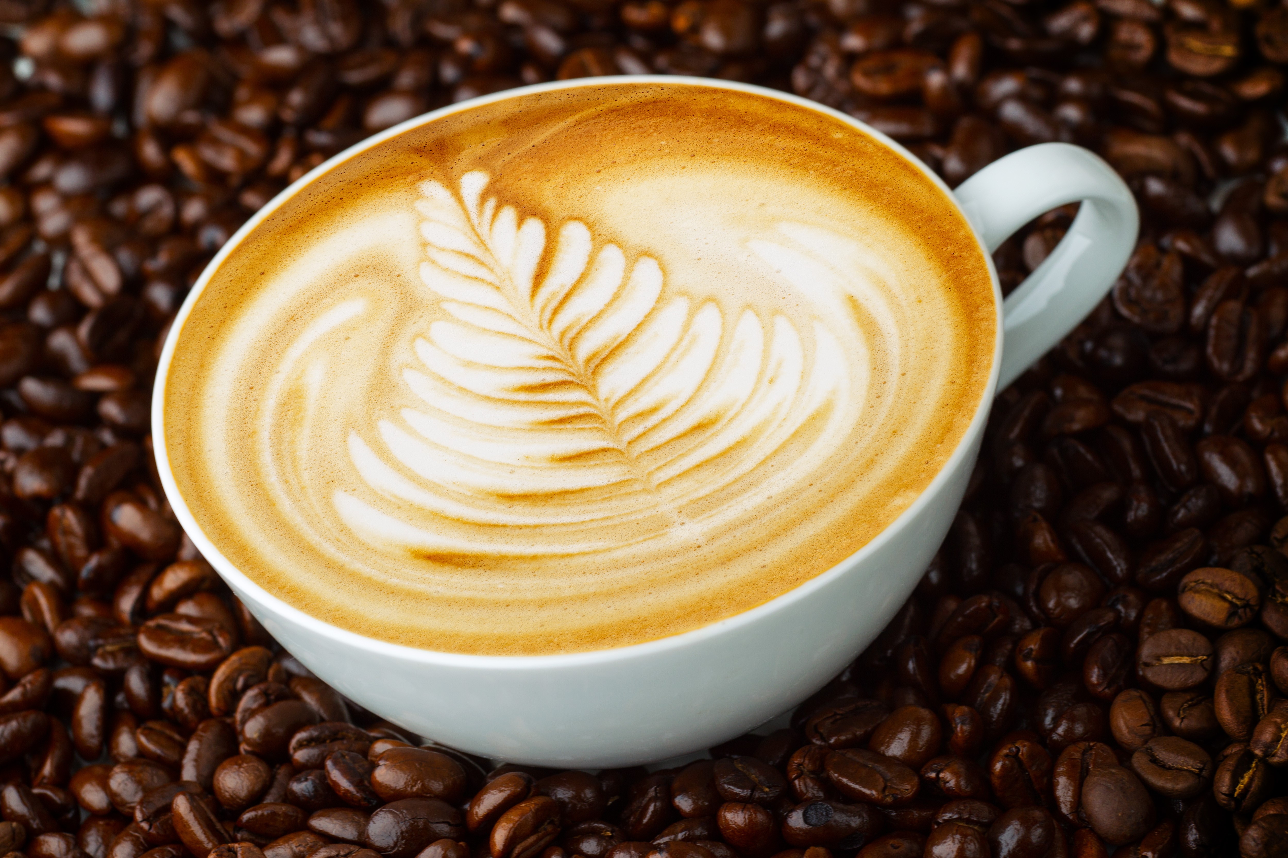 Cappuccino with latte art on coffee beans HD Wallpaper