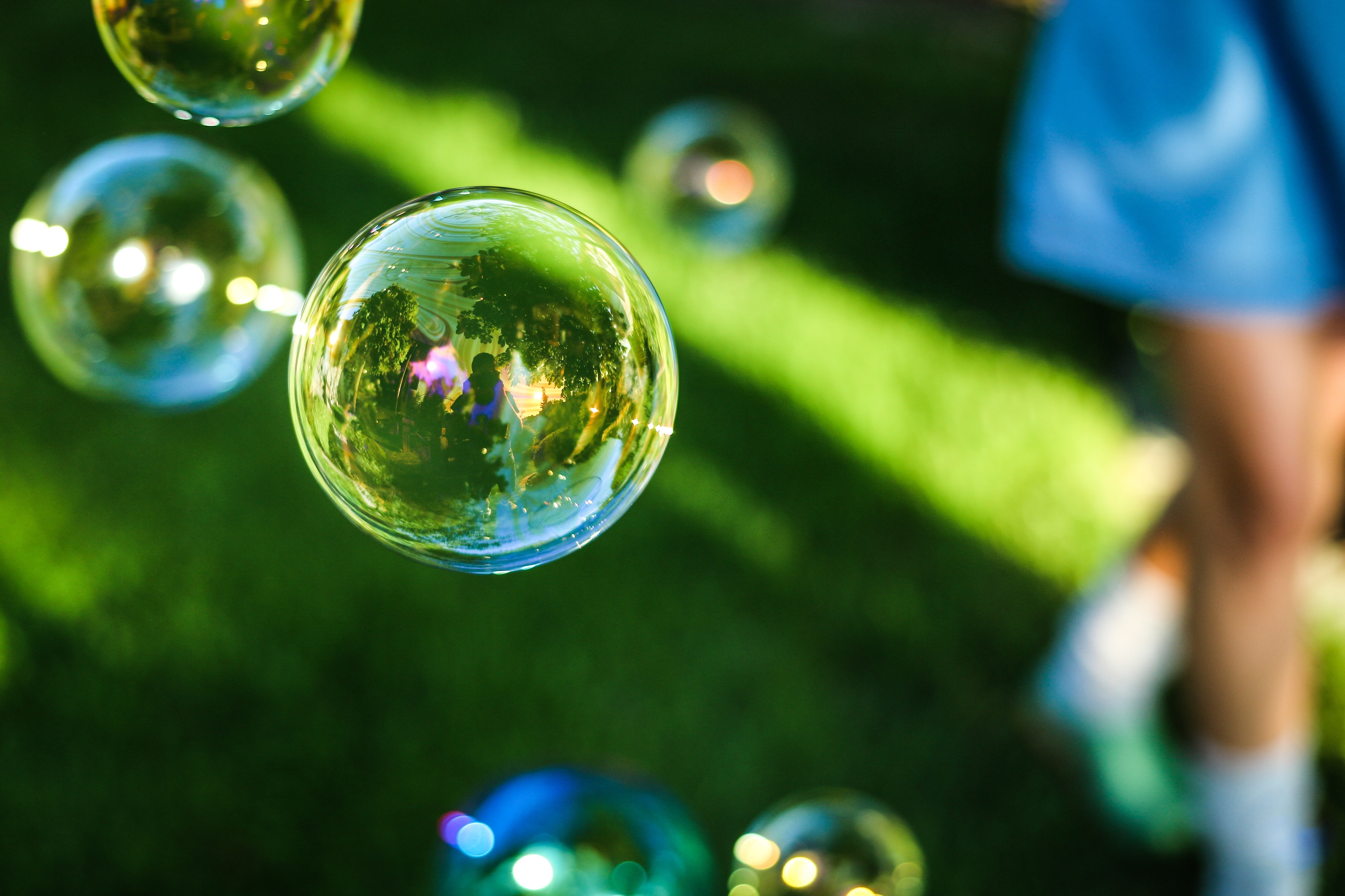 Soap bubbles floating in grass with person in background HD Wallpaper