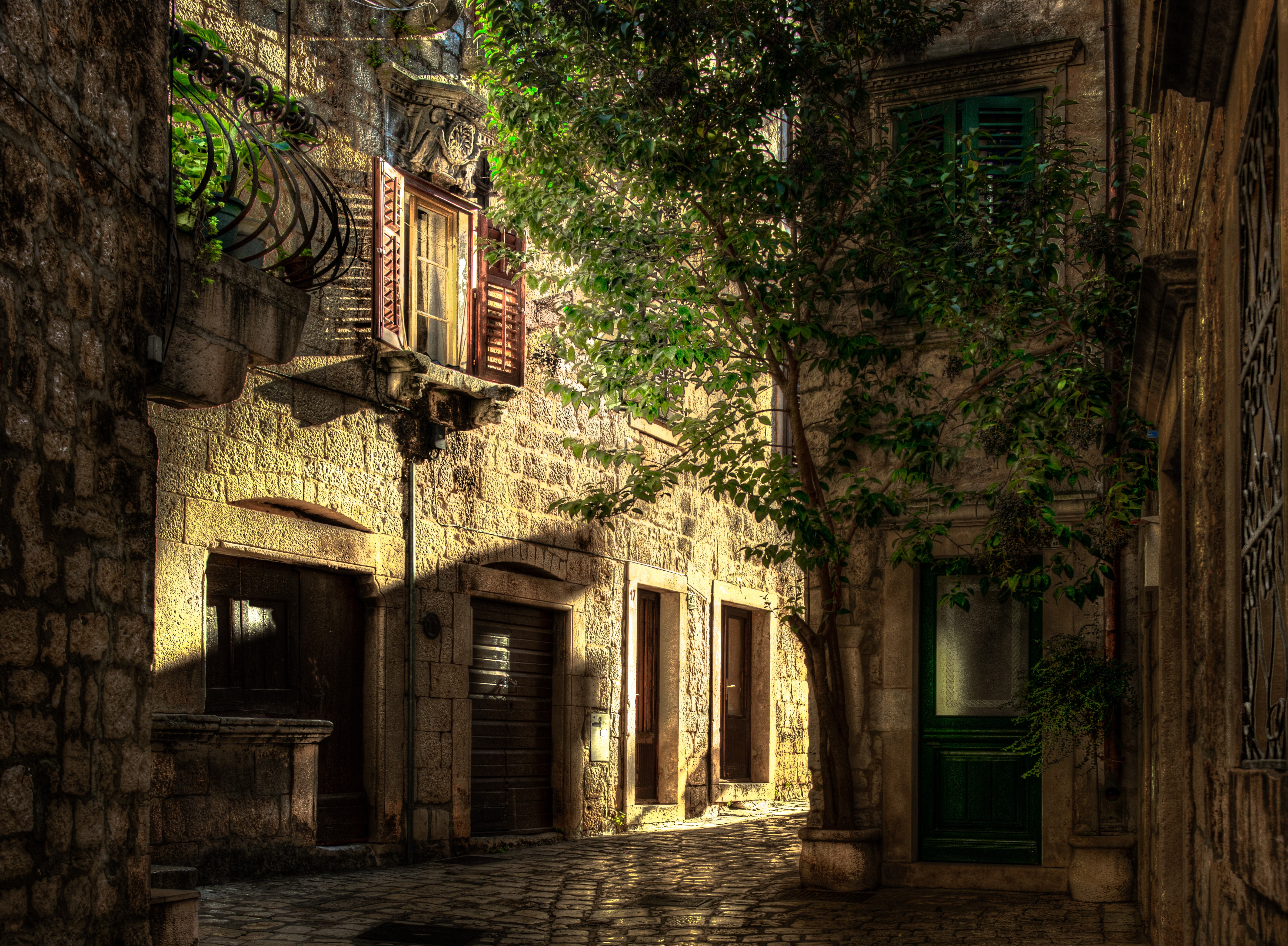 Street in Hvar, Croatia with stone buildings and a tree HD Wallpaper