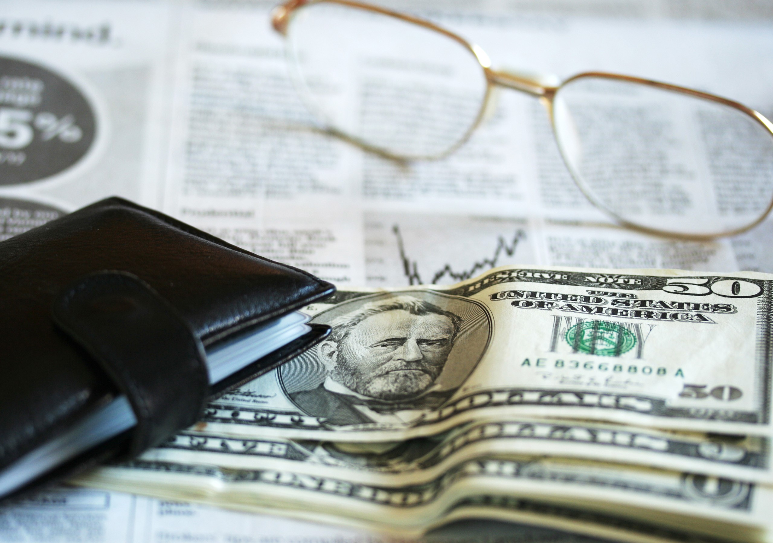 Fifty dollar bills with wallet and glasses on newspaper HD Wallpaper