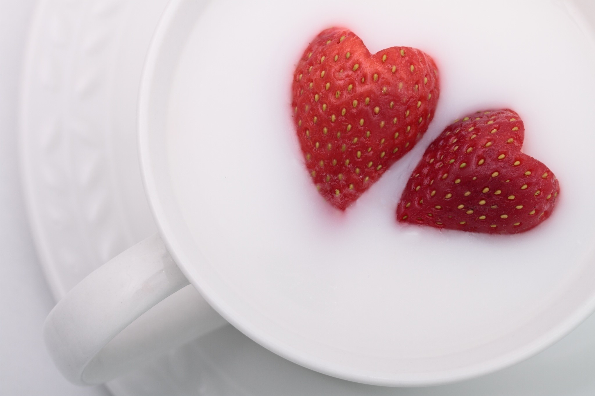 Two heart-shaped strawberries in milk HD Wallpaper