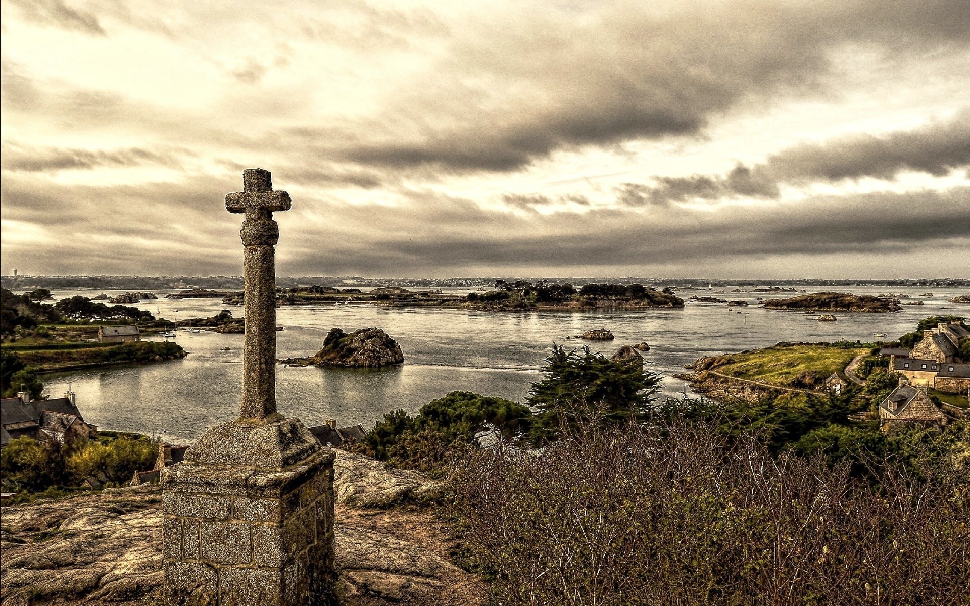 Stone cross overlooking a coastal village and islands HD Wallpaper
