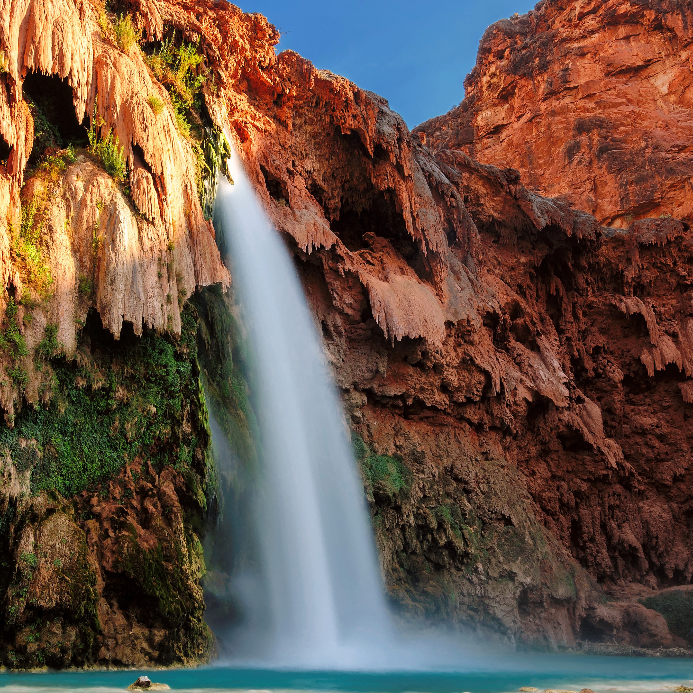 Waterfall cascading over red rocks into a turquoise pool HD Wallpaper