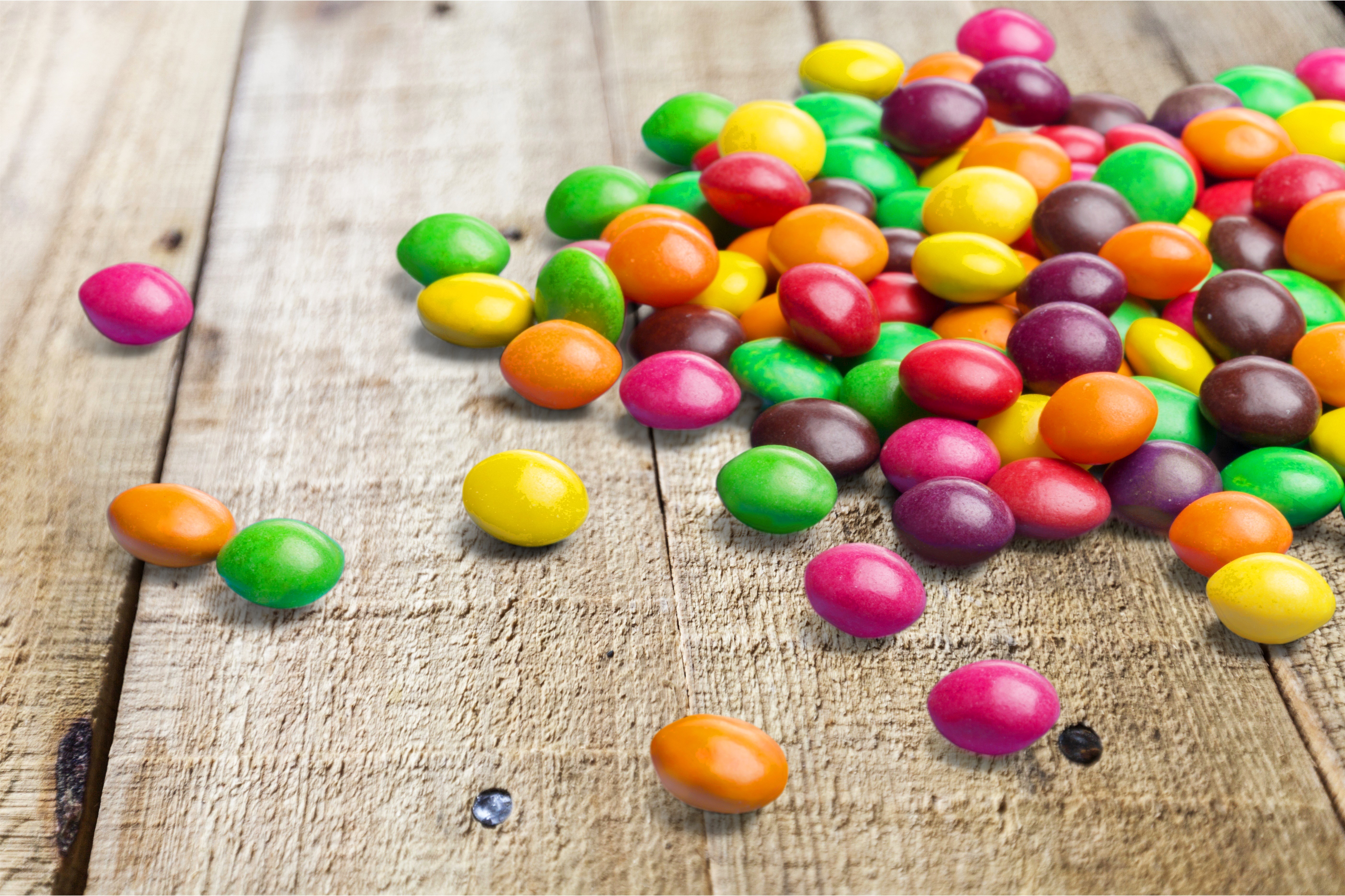 Colorful candies scattered on wooden planks HD Wallpaper