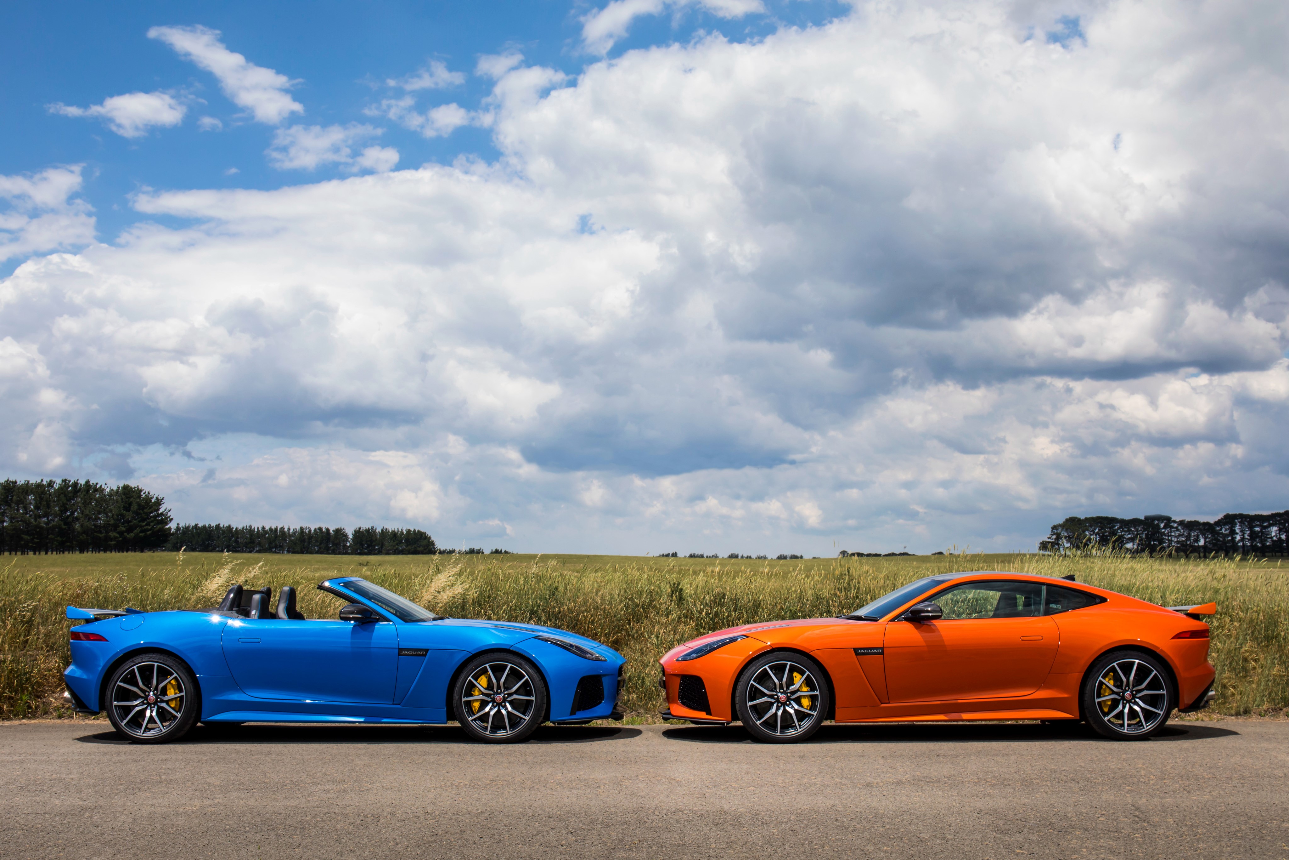 Two Jaguar F-Type cars, blue convertible and orange coupe HD Wallpaper