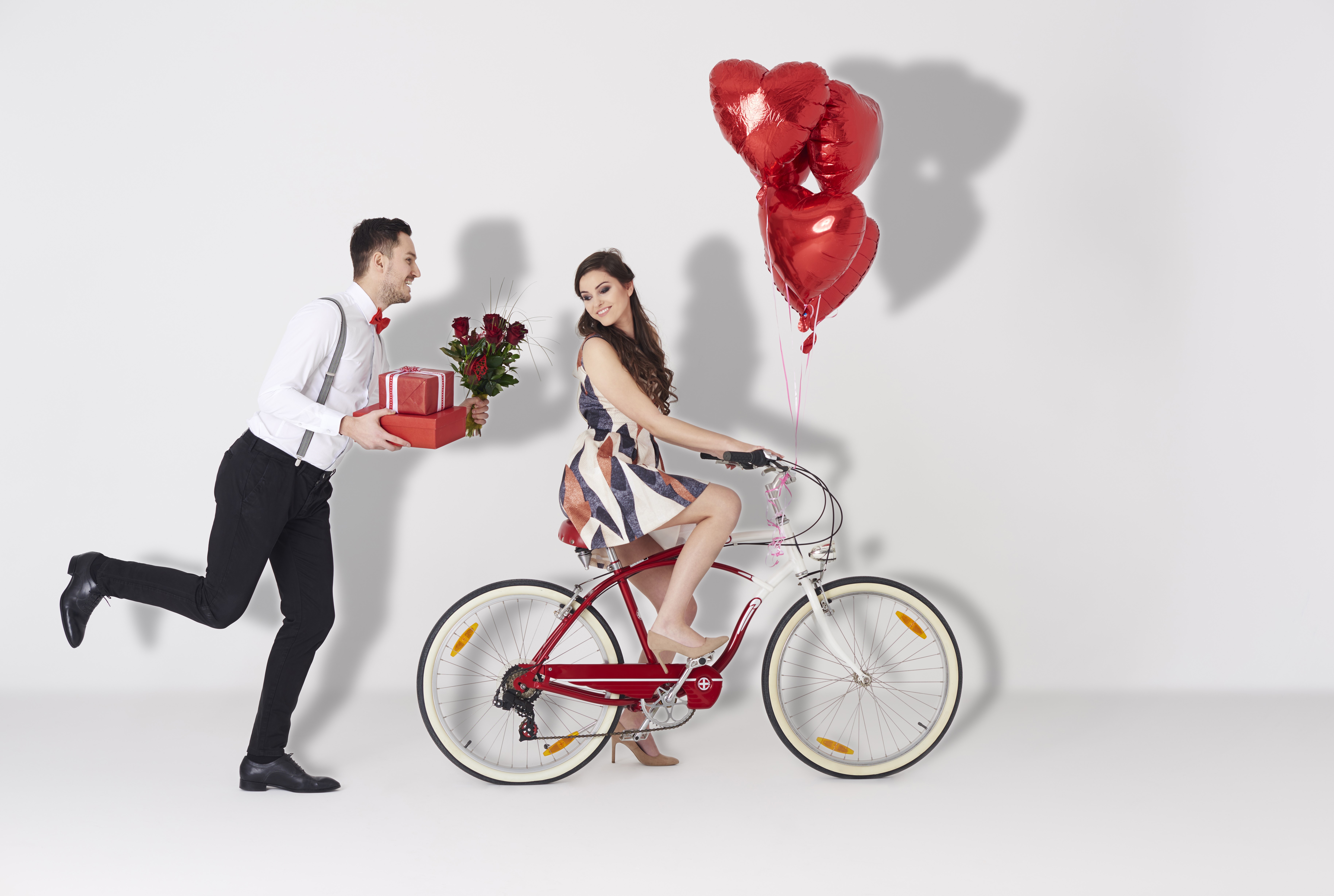 Man with gifts and roses chases woman on bicycle with balloons HD Wallpaper