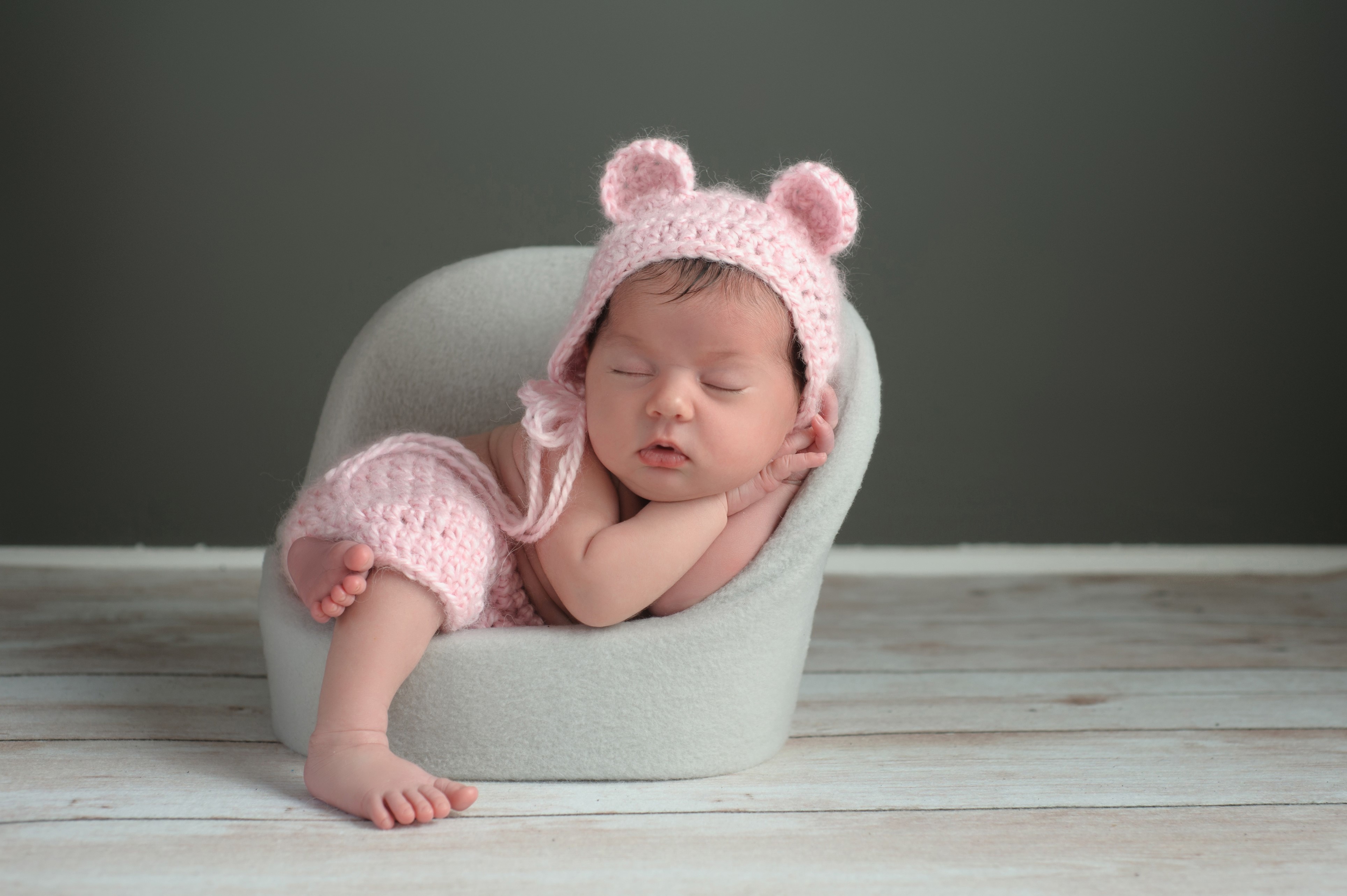Newborn baby sleeping in a chair wearing a pink hat HD Wallpaper