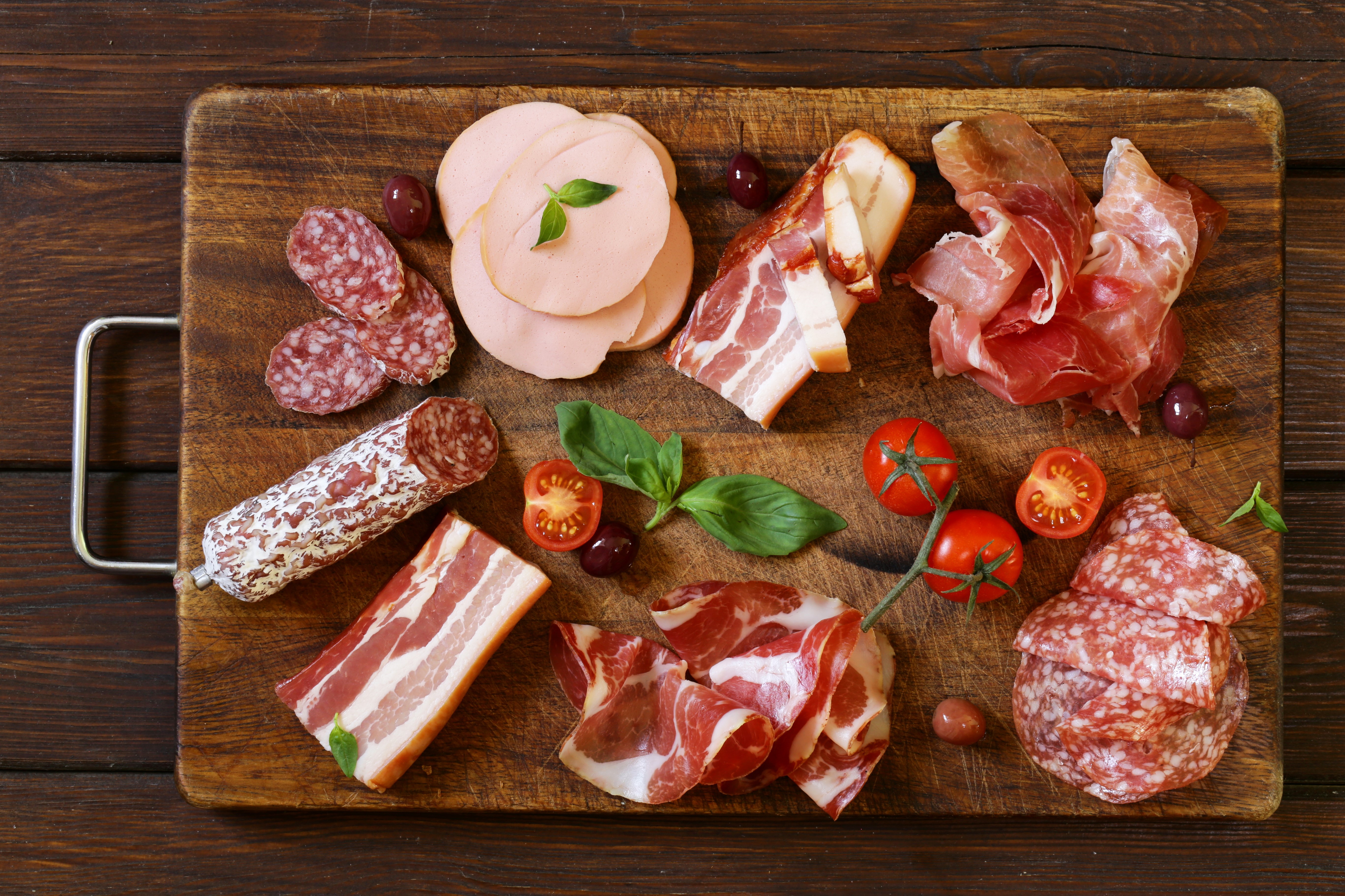 Meat products on a cutting board with tomatoes and olives HD Wallpaper