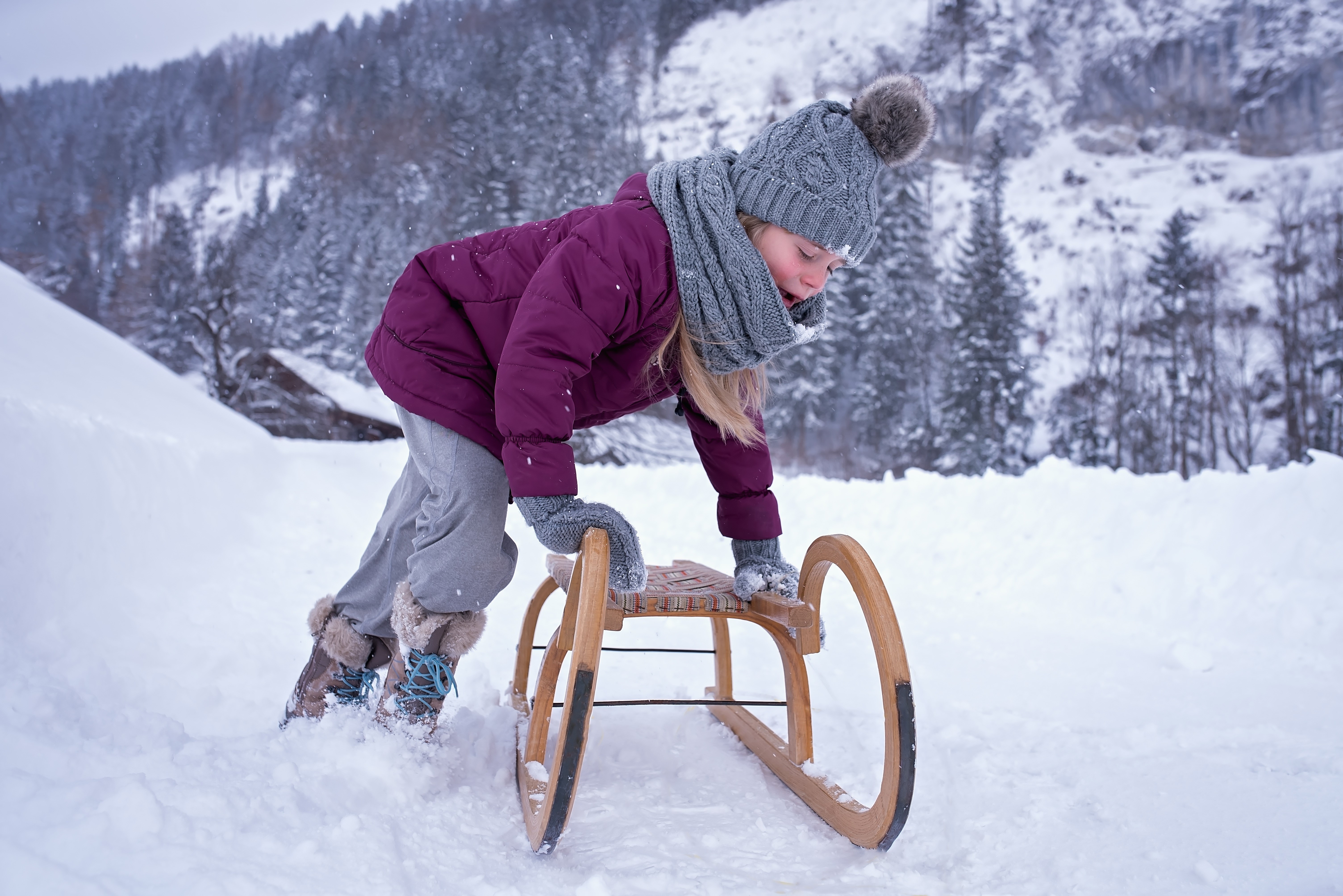 Girl in winter clothes with a sled in the snow HD Wallpaper