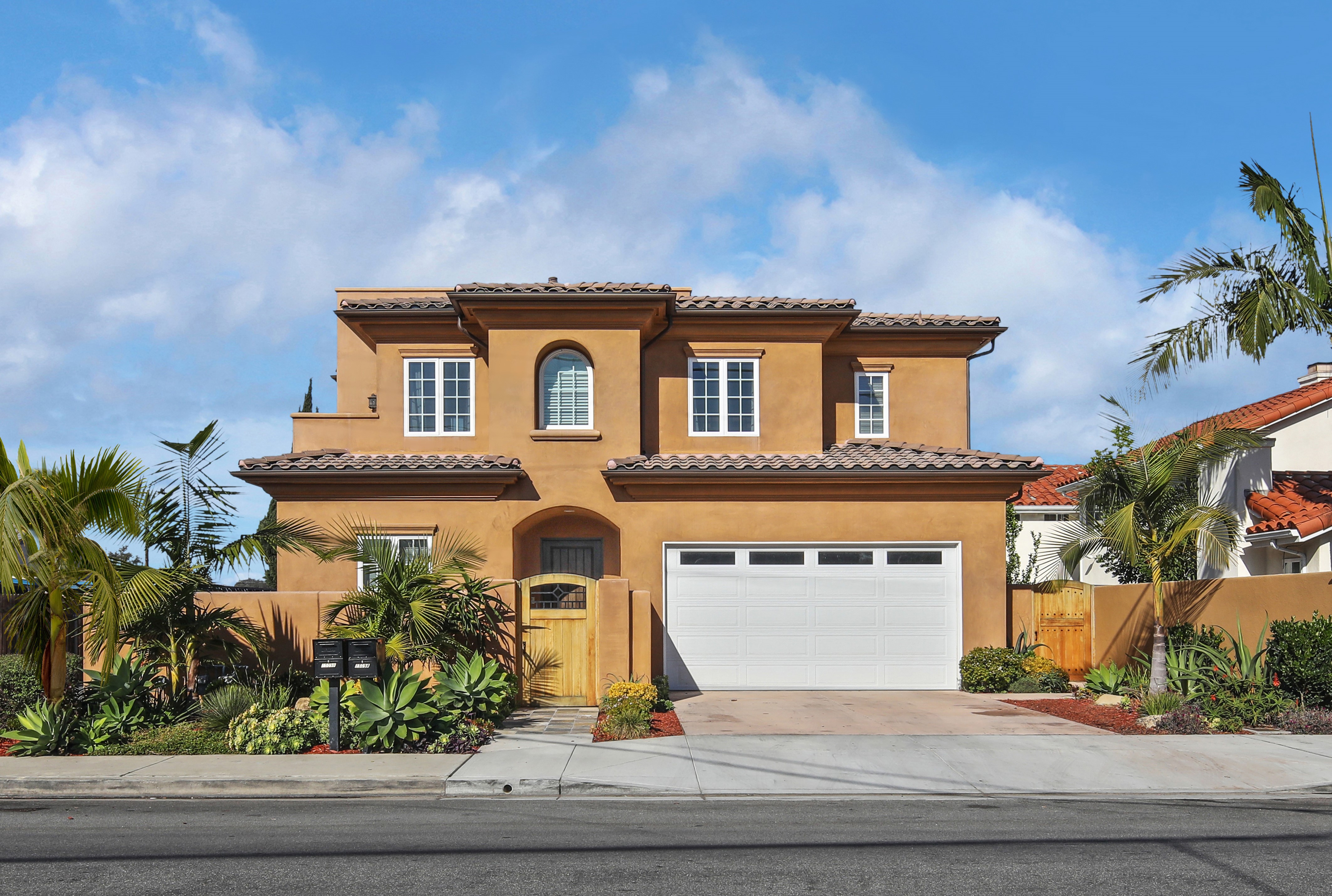 Orange stucco house with garage and palm trees HD Wallpaper
