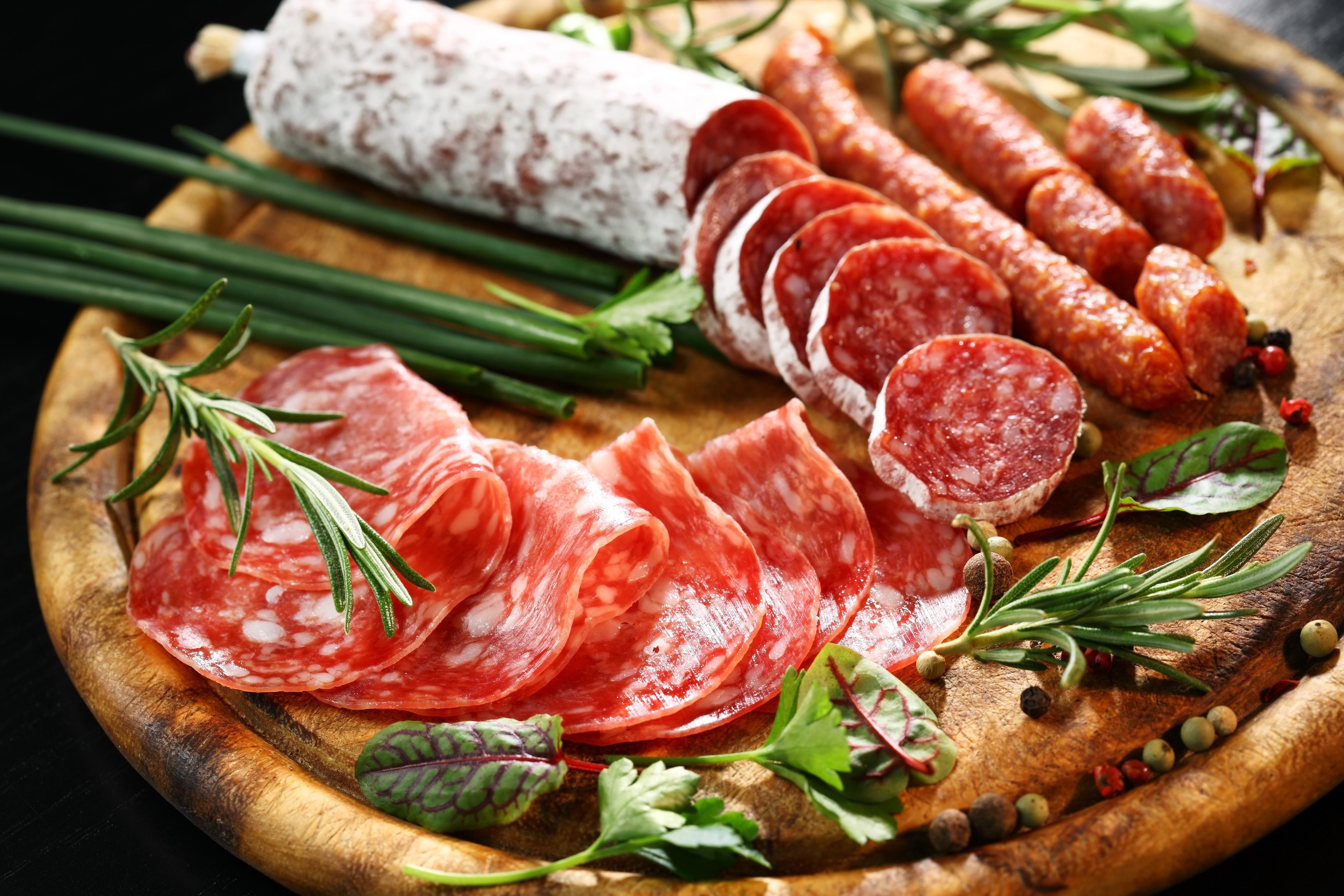 Sliced sausages and salami on a wooden board HD Wallpaper