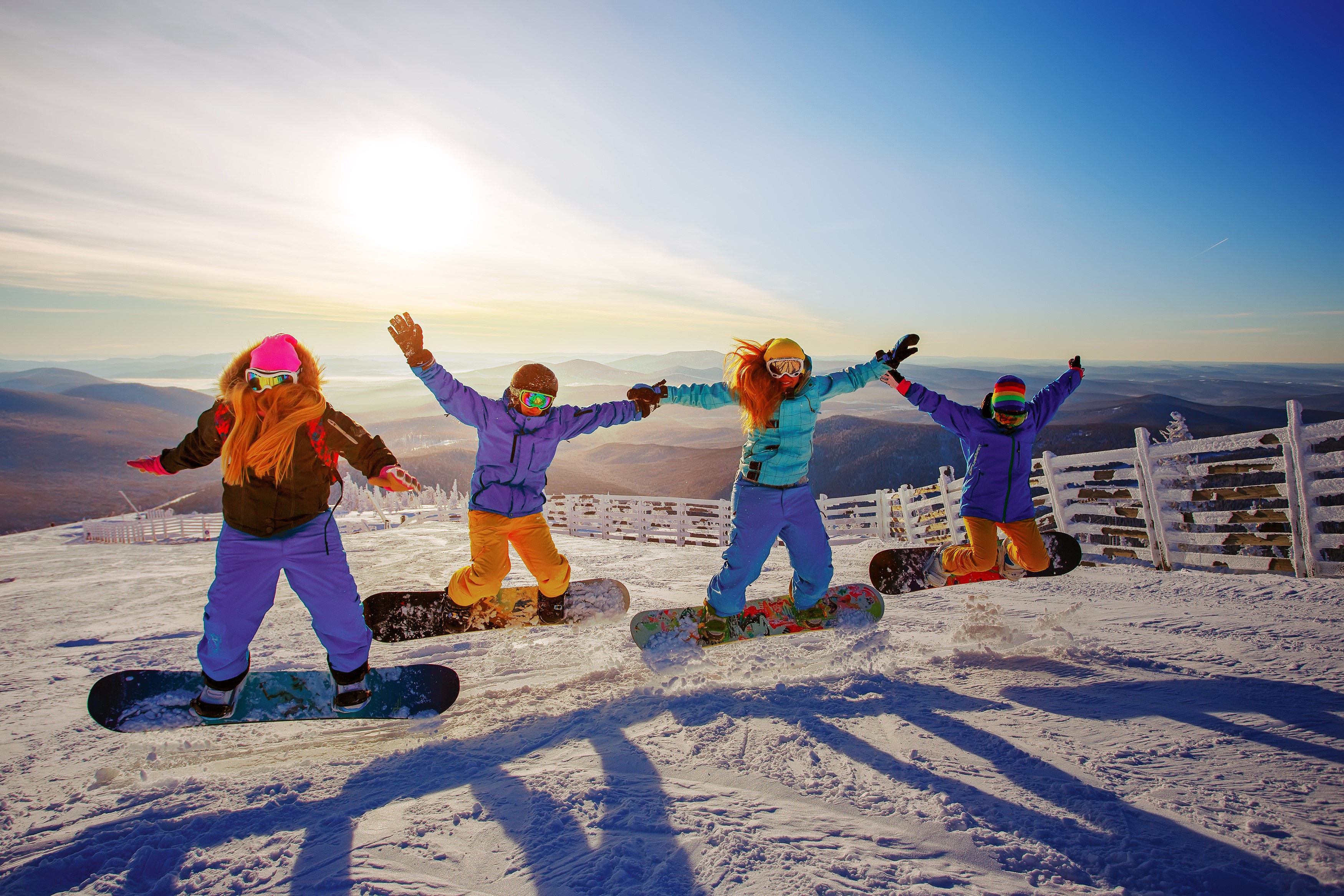 Four friends snowboarding and jumping on a snowy mountain HD Wallpaper