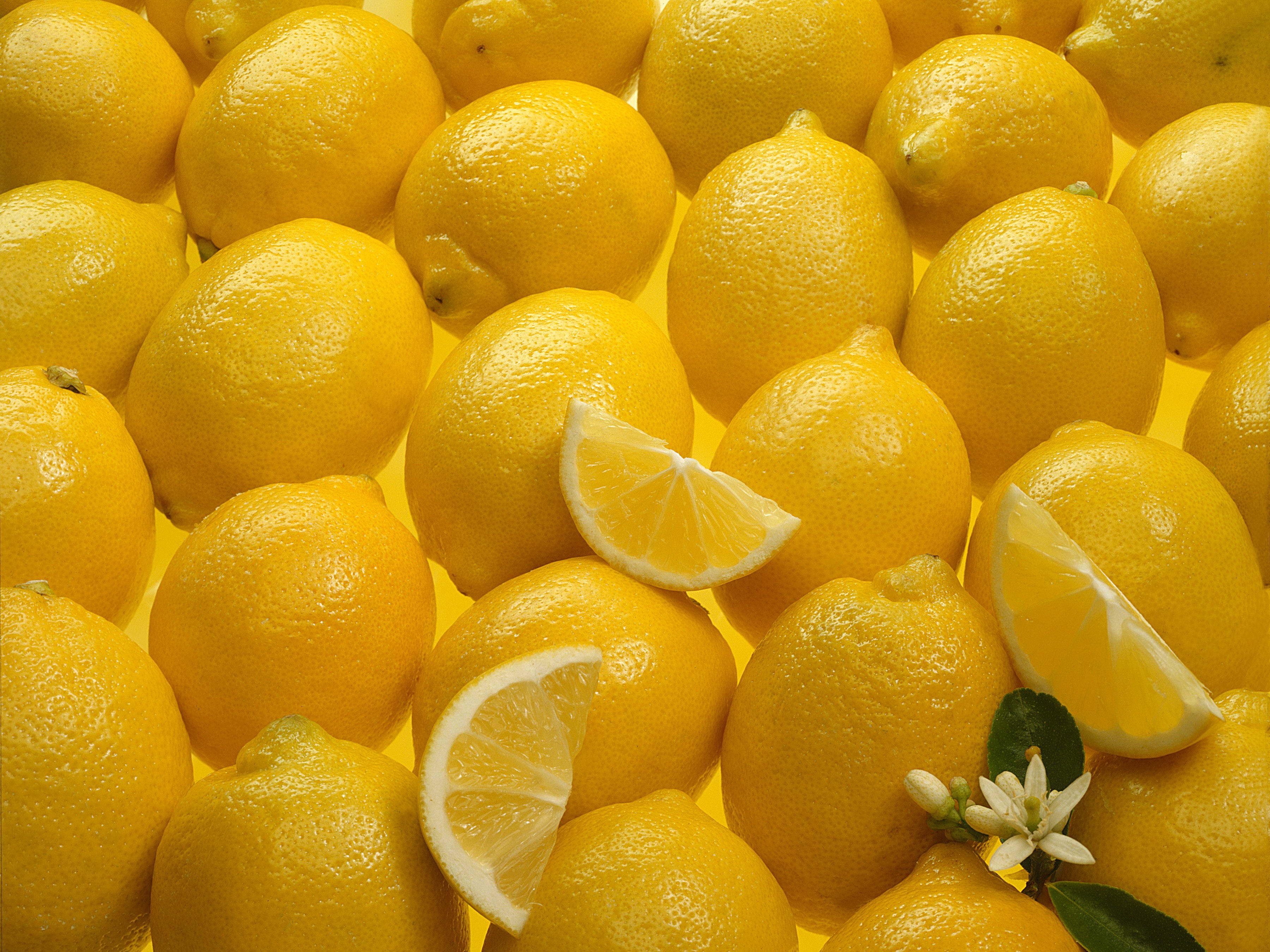 A pile of yellow lemons with slices and a flower HD Wallpaper