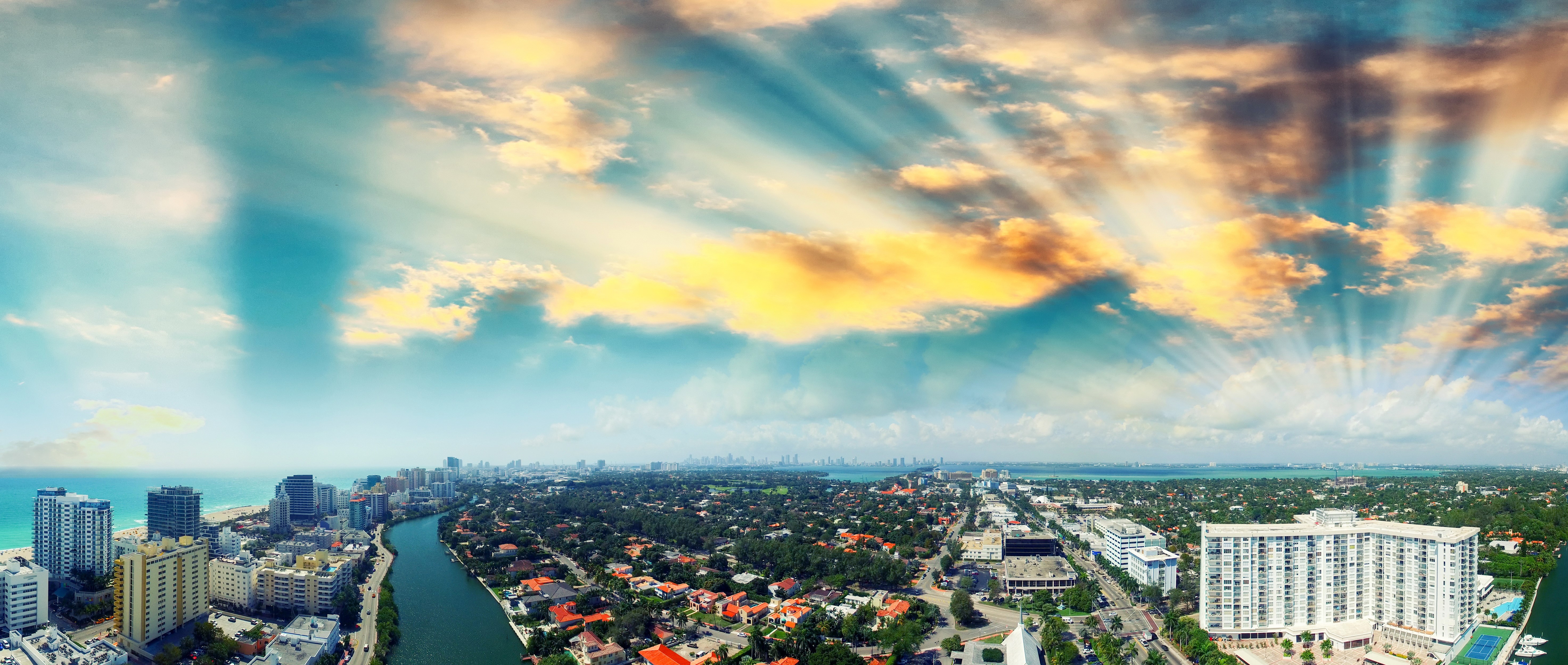 Miami skyline with river and ocean under dramatic sky HD Wallpaper
