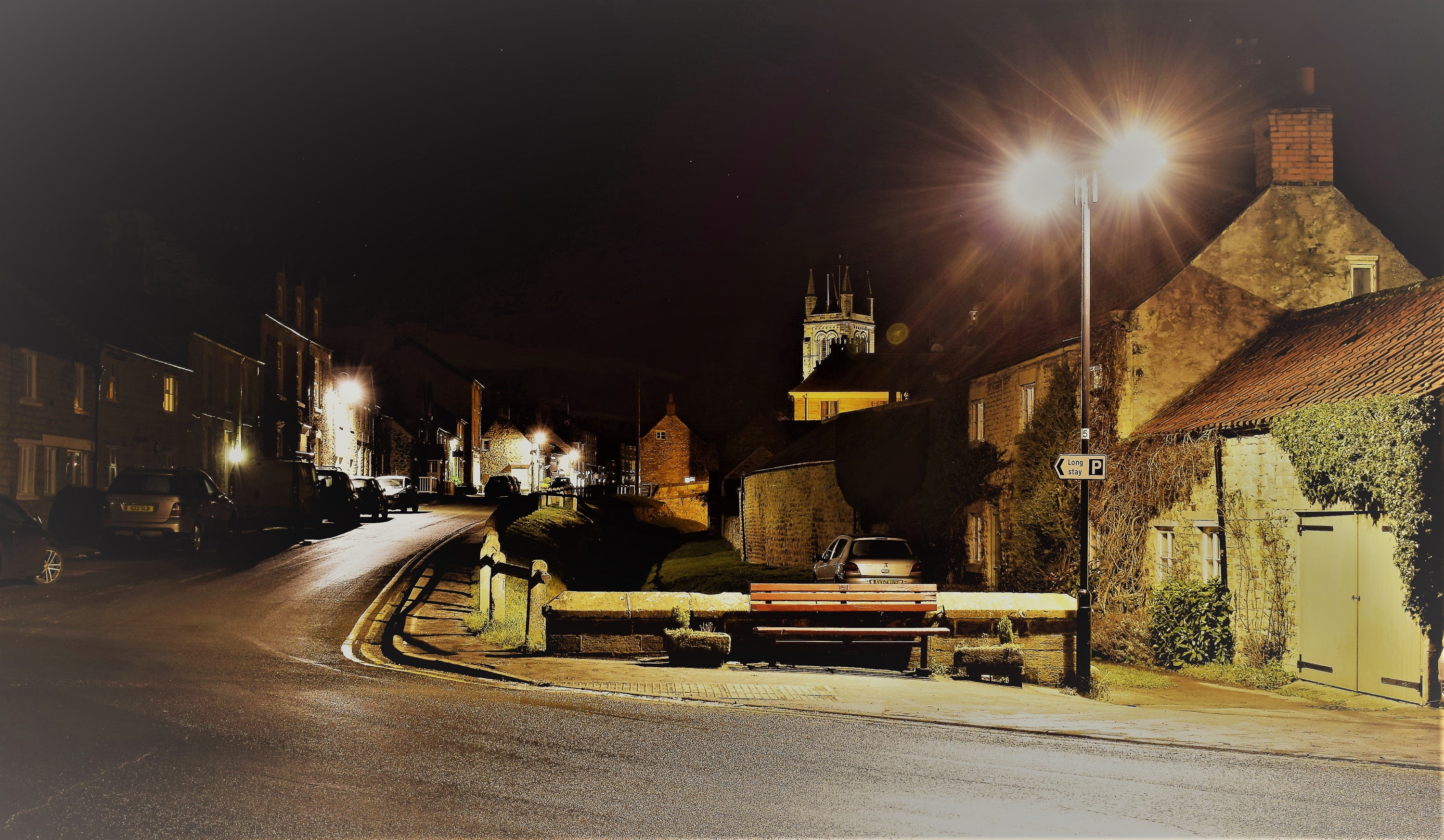 Night street scene in Helmsley, North Yorkshire, England with houses and street lights HD Wallpaper