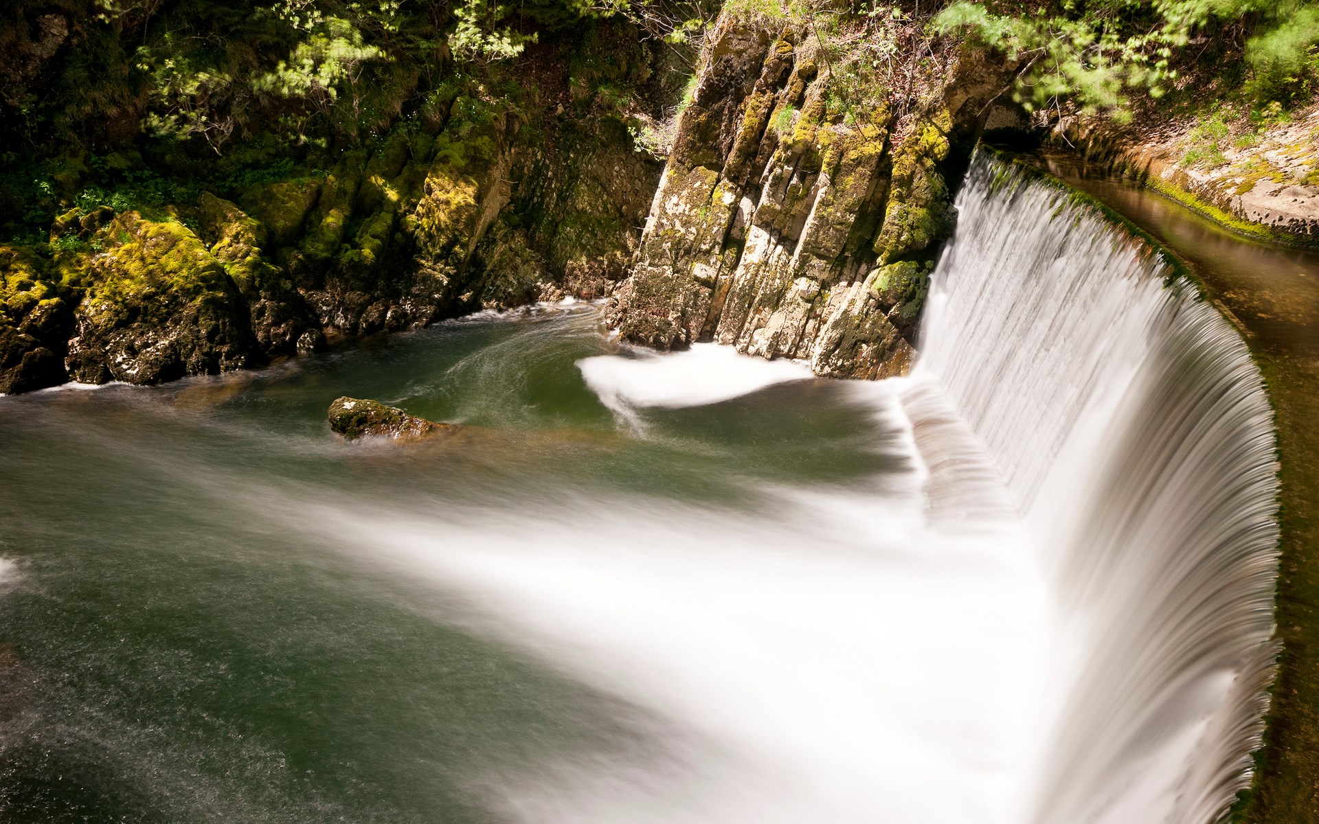 Waterfall cascading over rocks in a forest HD Wallpaper