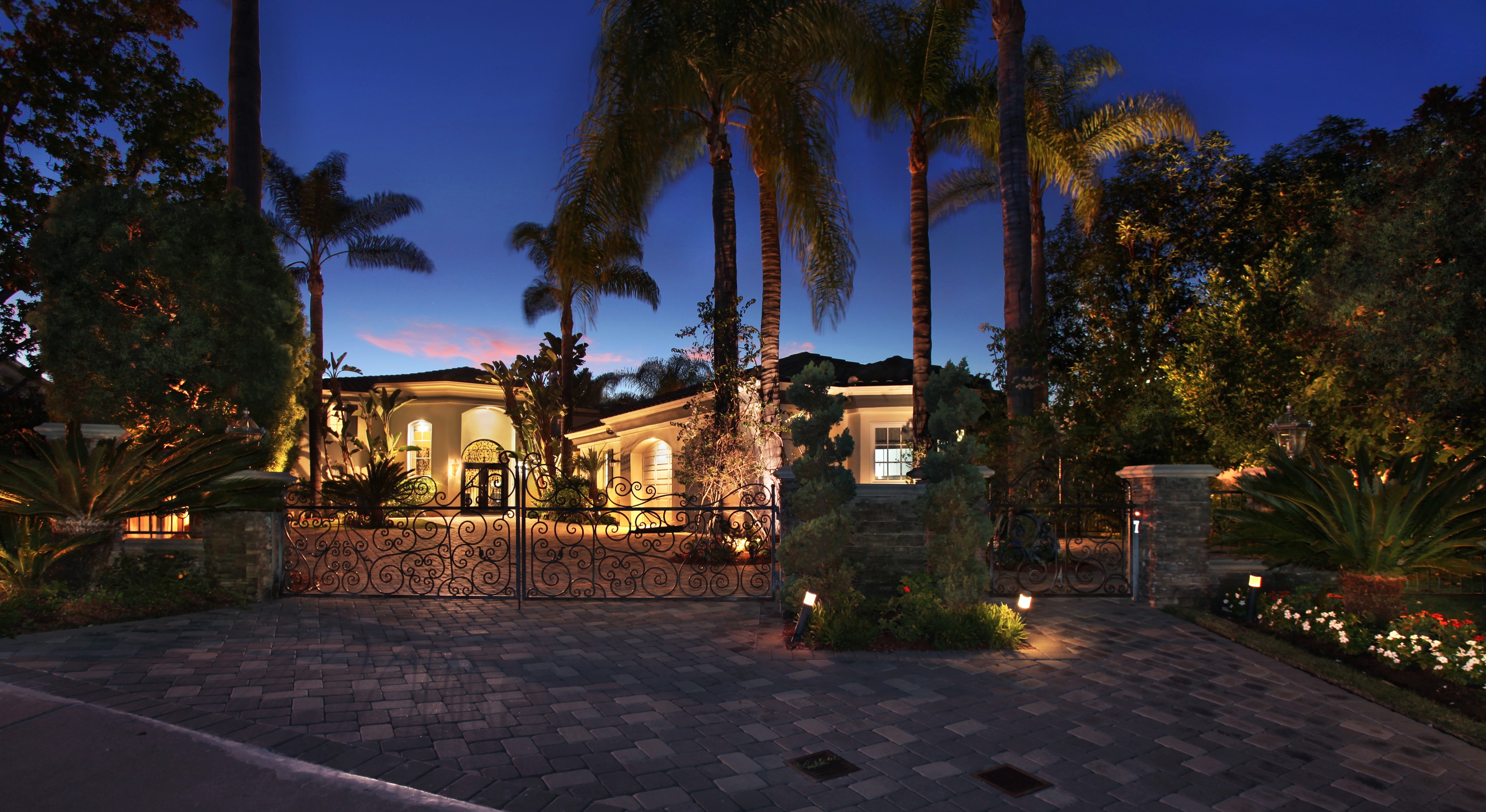 Luxury house with ornate gates and palm trees at dusk HD Wallpaper