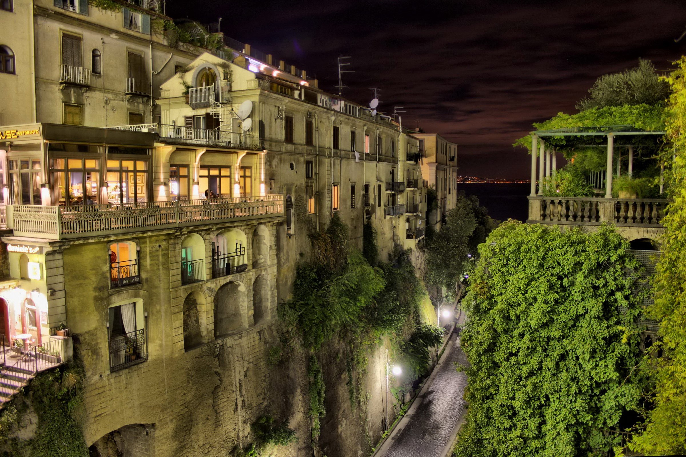 Night view of buildings on a cliffside street in Sorrento, Italy HD Wallpaper