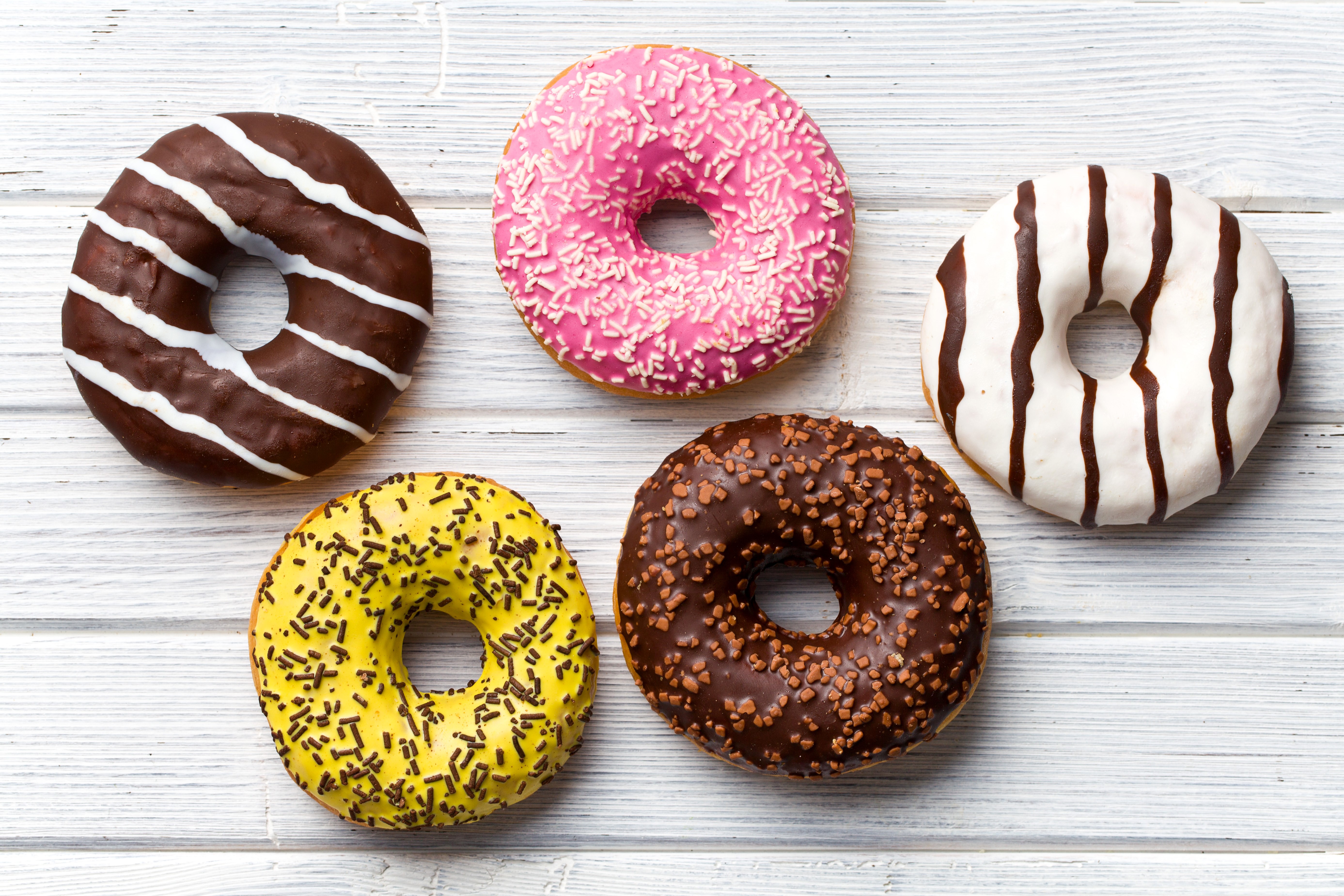 Assortment of colorful donuts on wooden planks HD Wallpaper