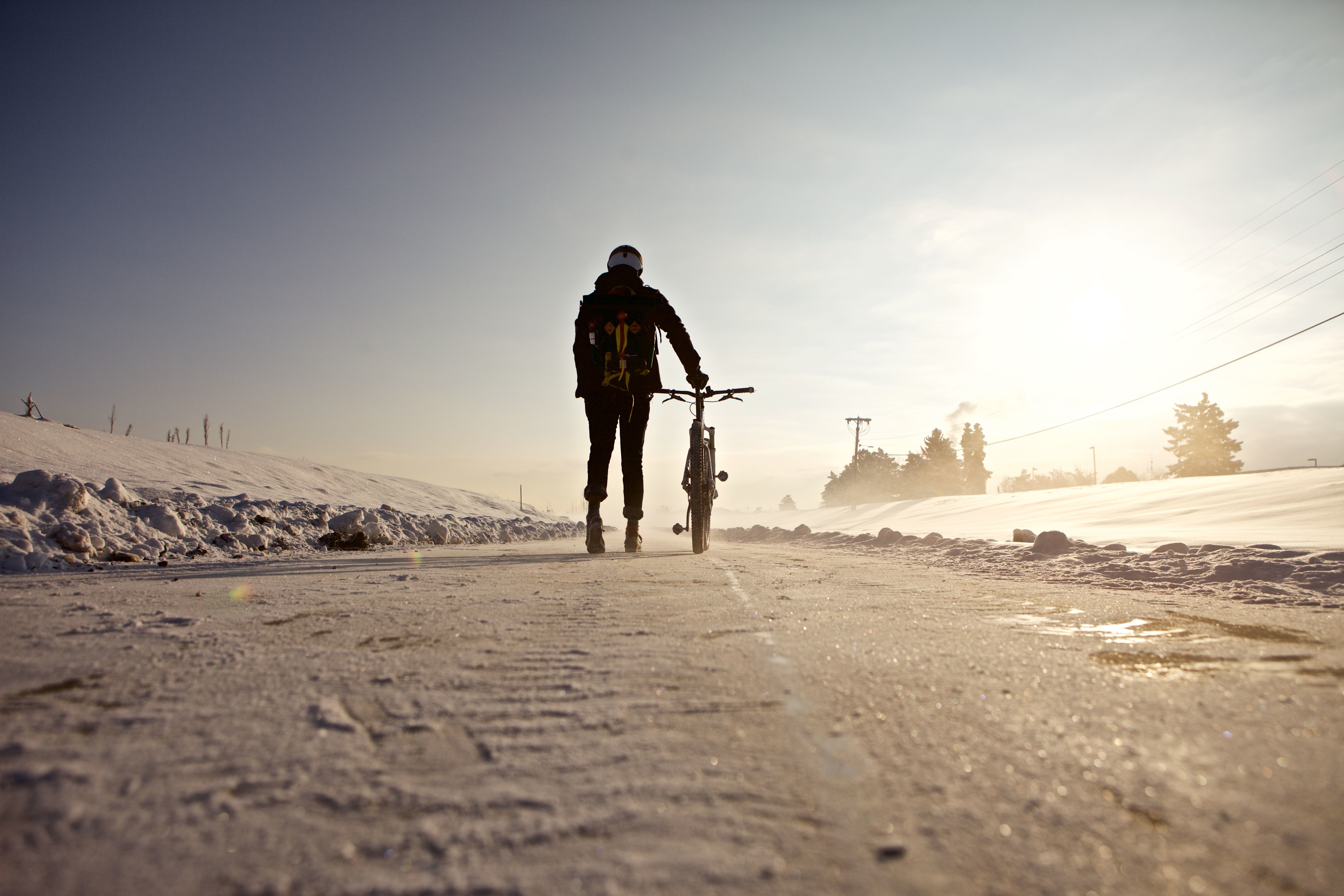Person with bicycle walking on snowy road HD Wallpaper
