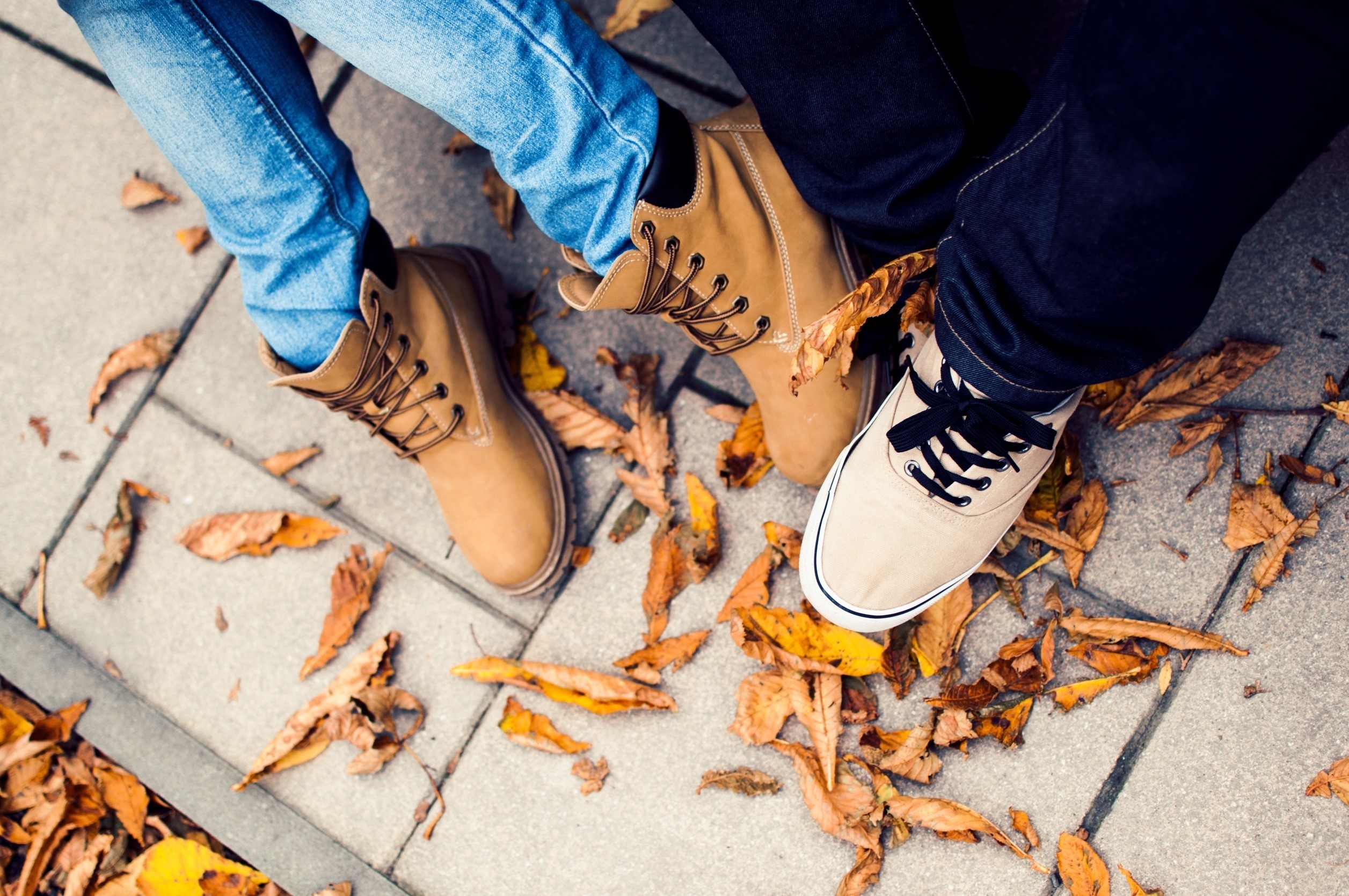 Two people wearing boots and jeans on autumn leaves HD Wallpaper