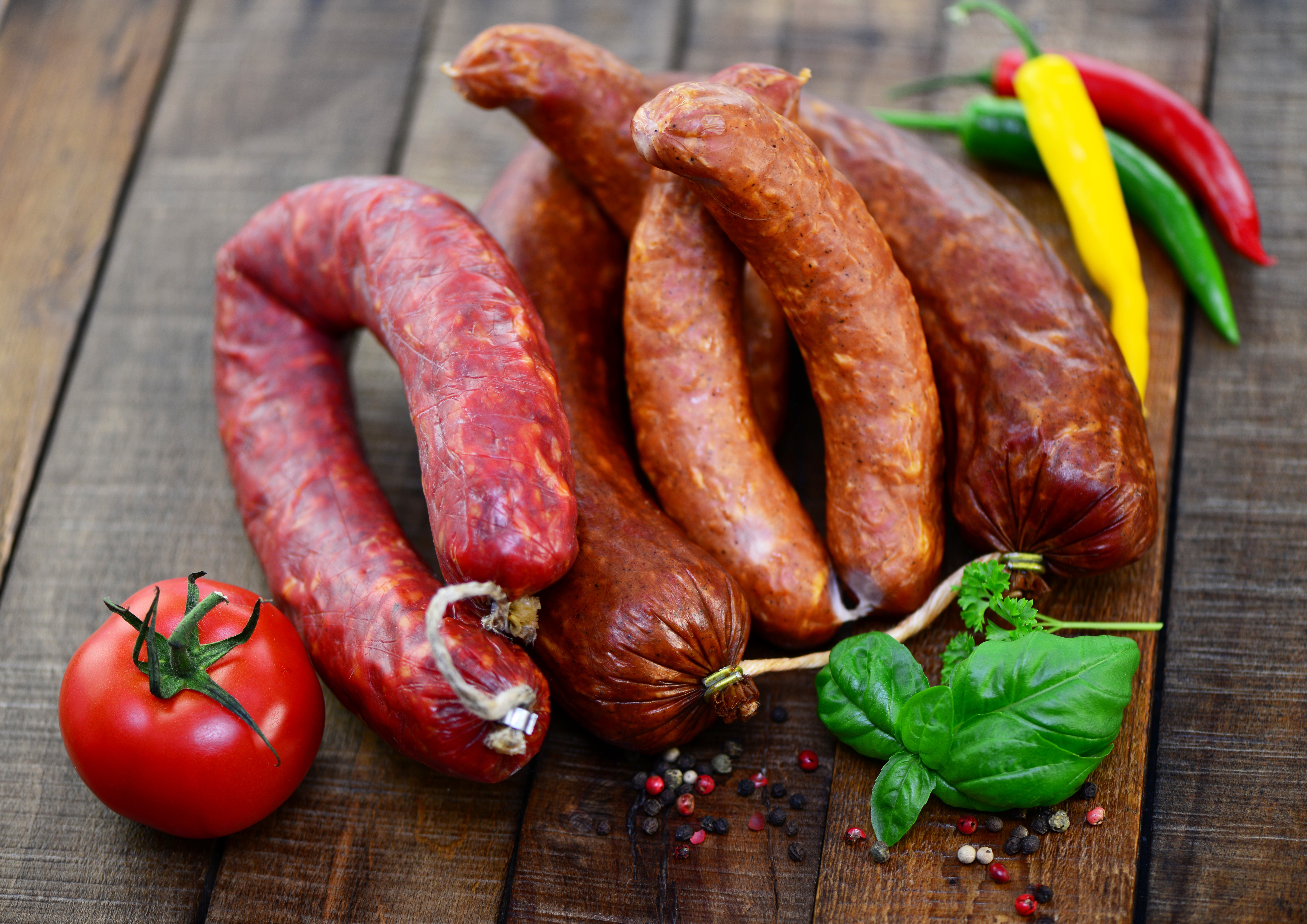 Sausages with tomatoes and chili peppers on wood HD Wallpaper