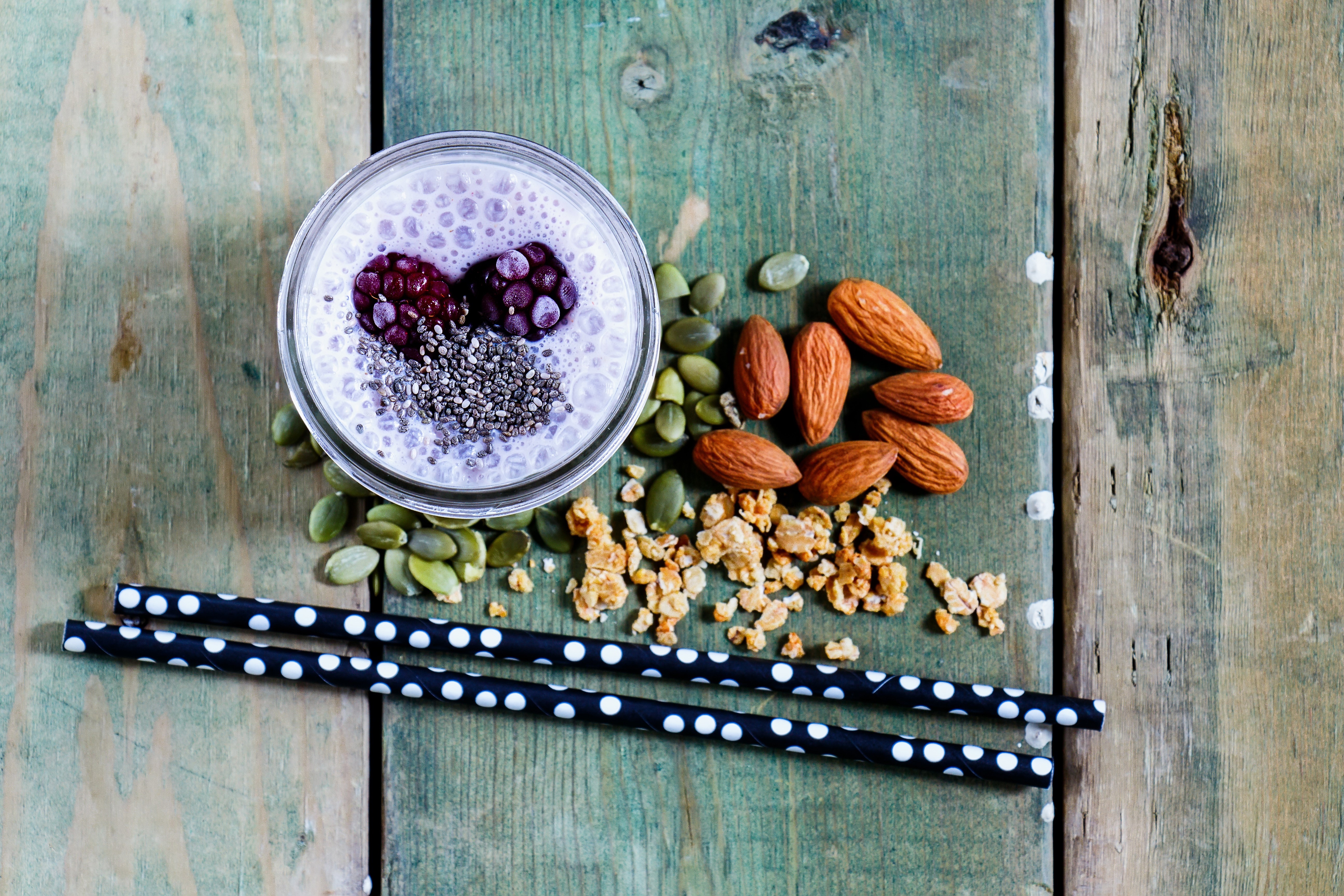Smoothie with berries, chia seeds, almonds, and pumpkin seeds on wood HD Wallpaper