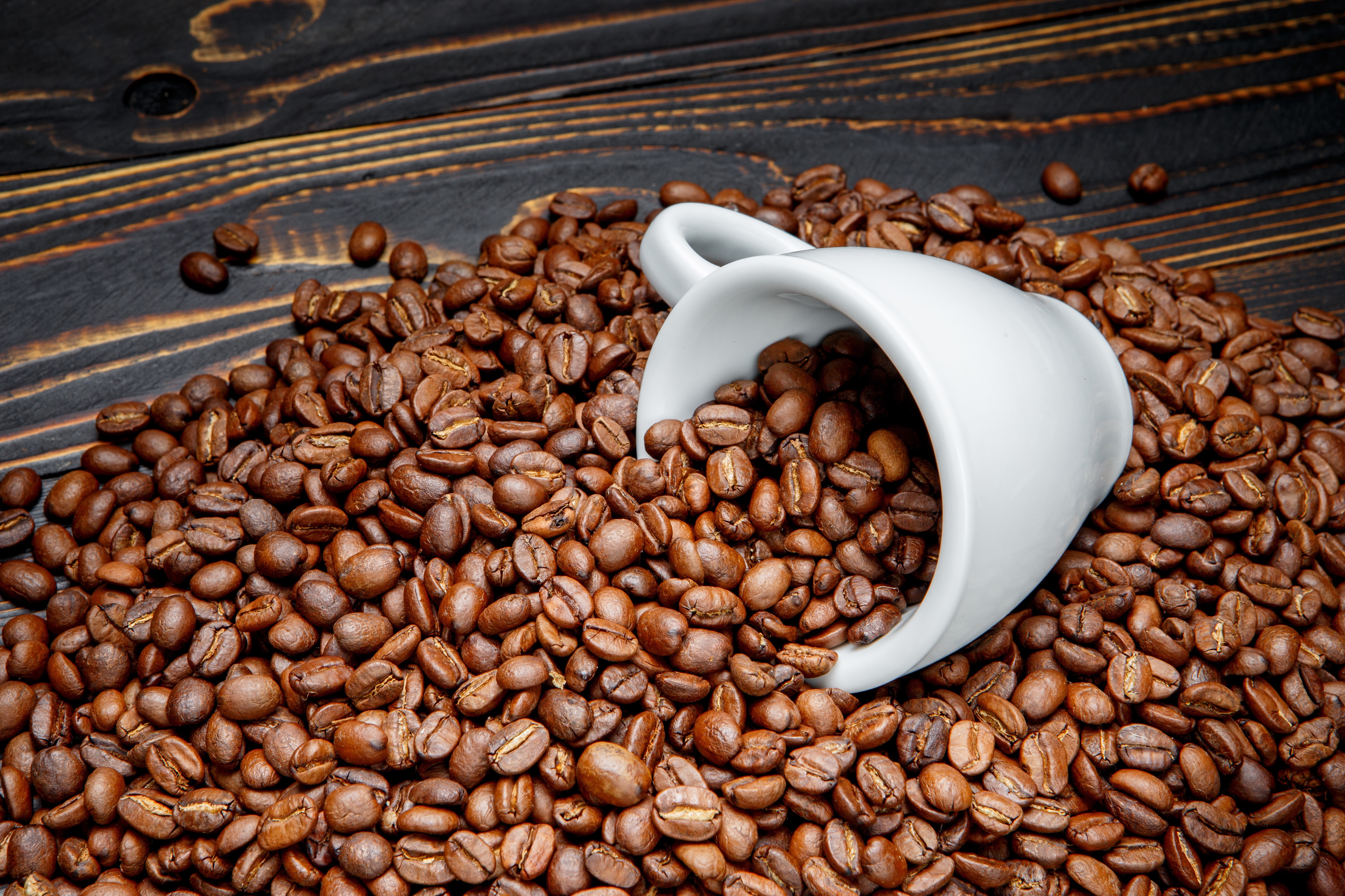 Coffee beans spilling from a cup on wood planks HD Wallpaper