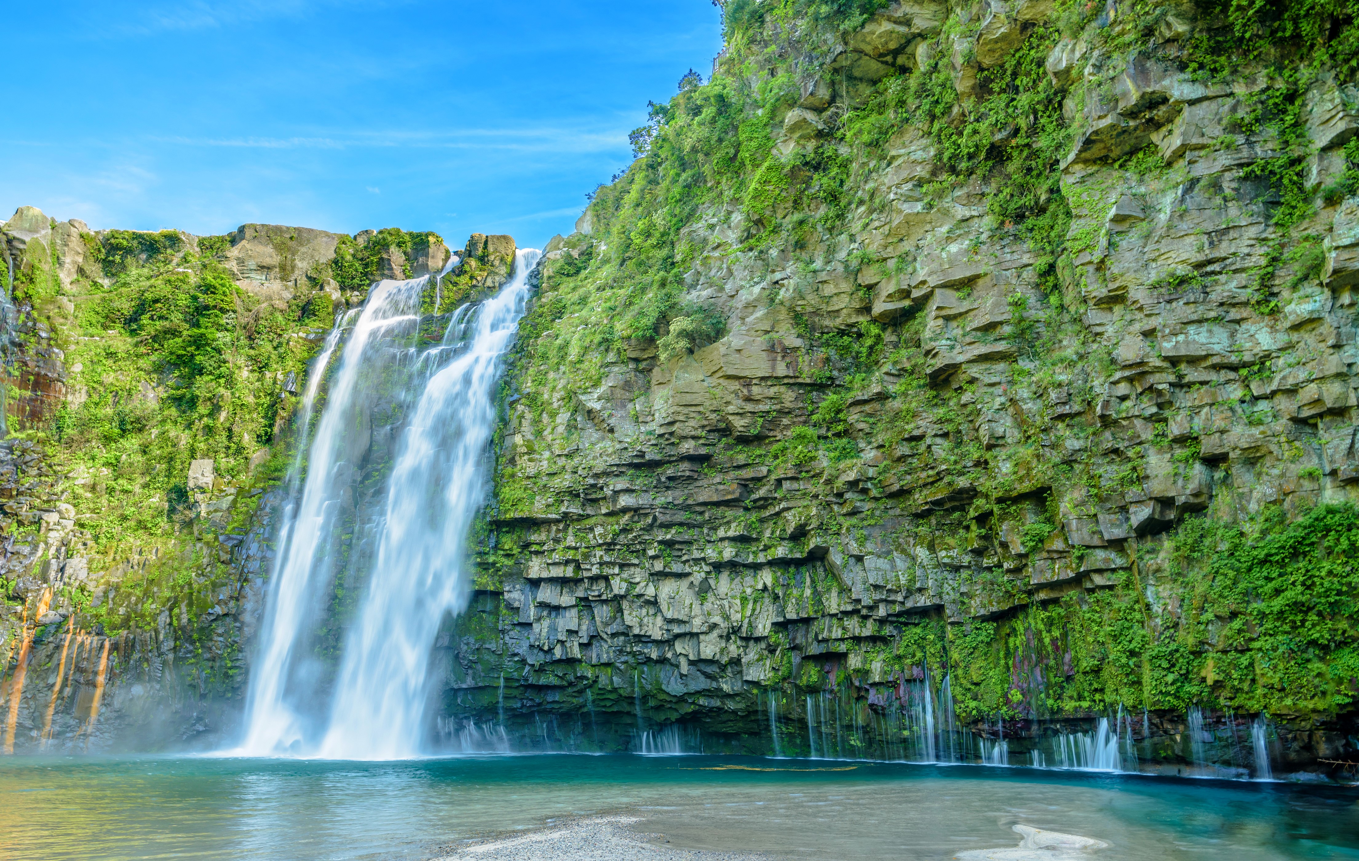 4K Waterfall cascading down a rocky cliff HD Wallpaper