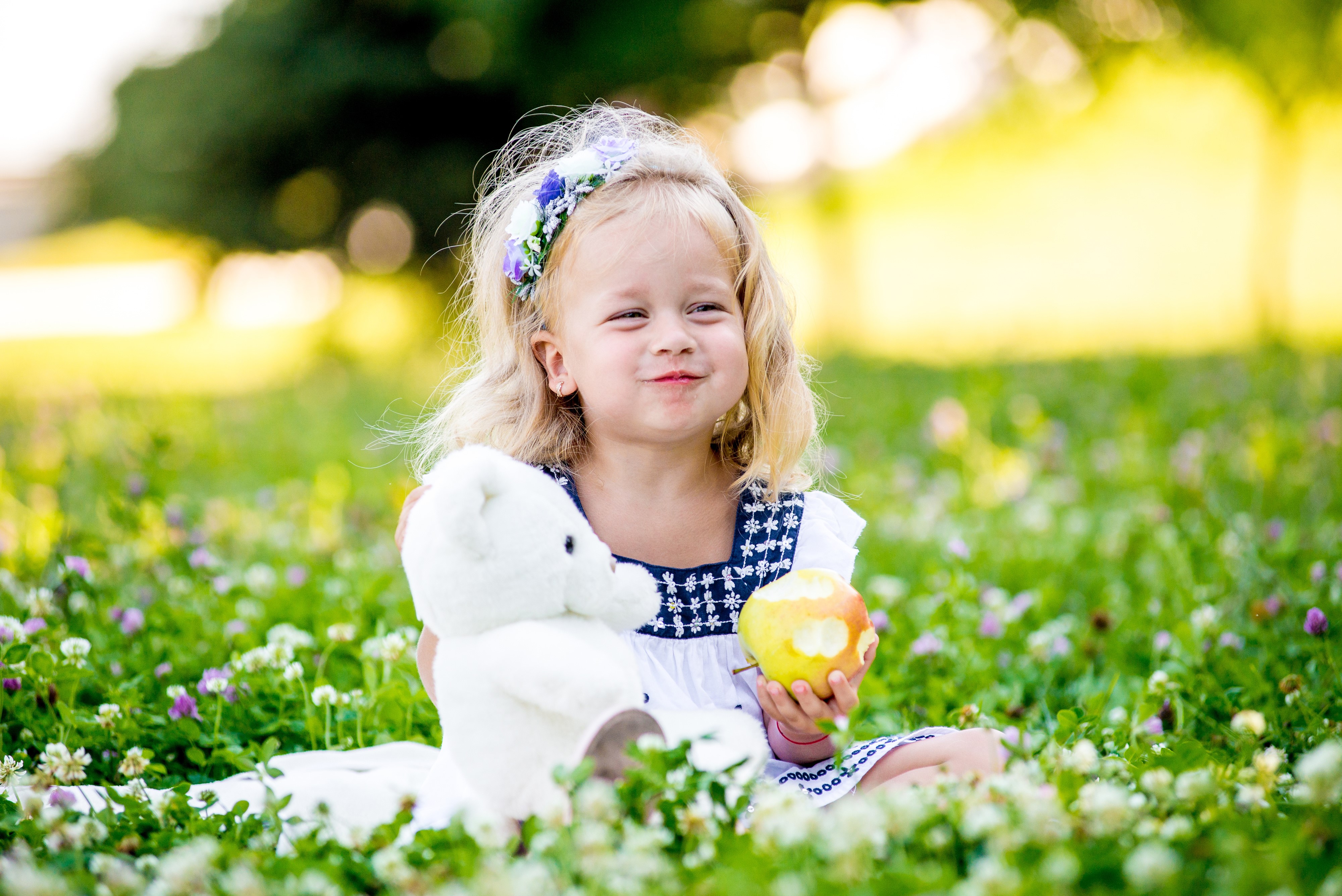 Little girl with teddy bear and apple in field HD Wallpaper