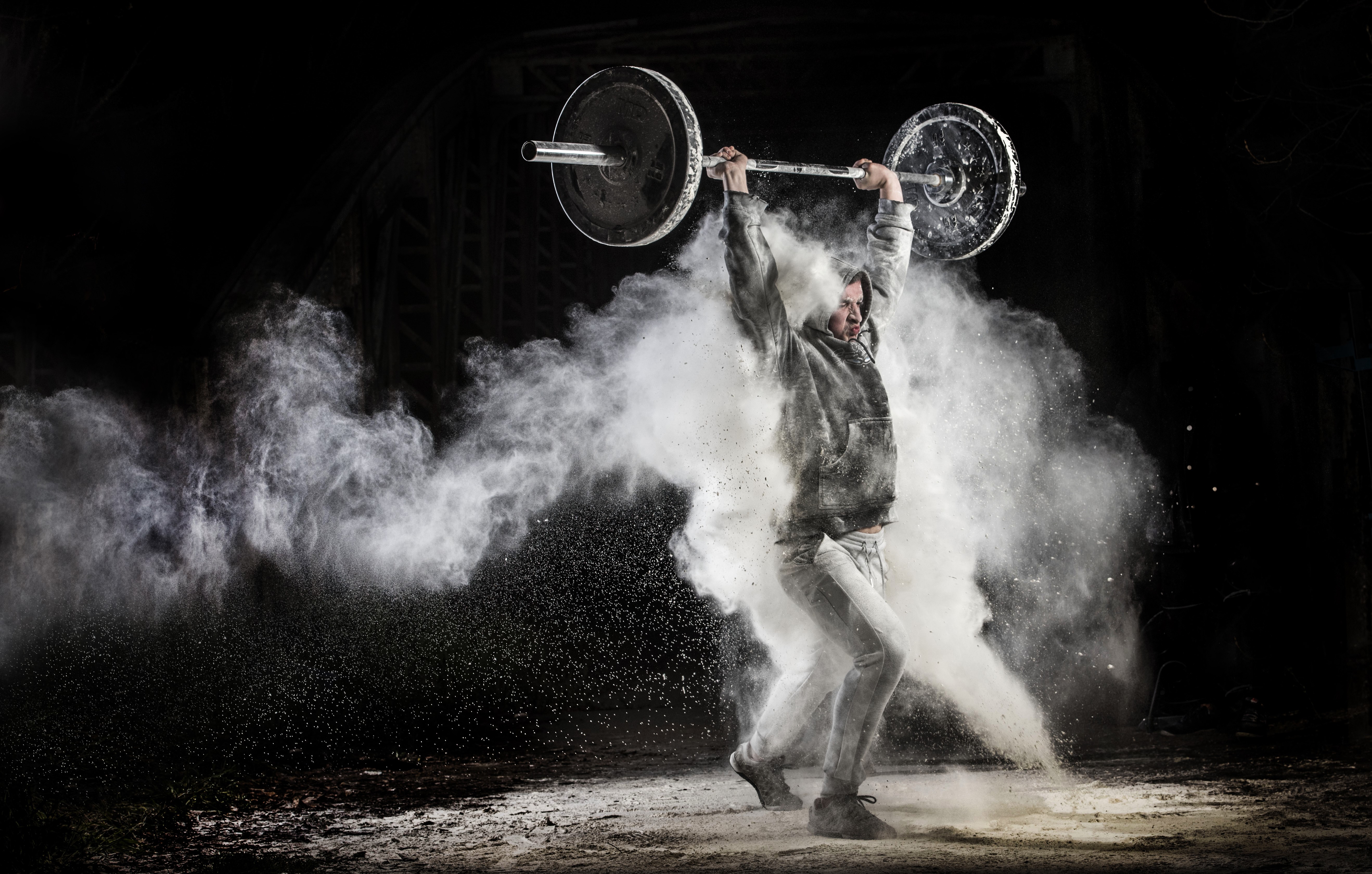 Man lifting barbell with white powder explosion HD Wallpaper